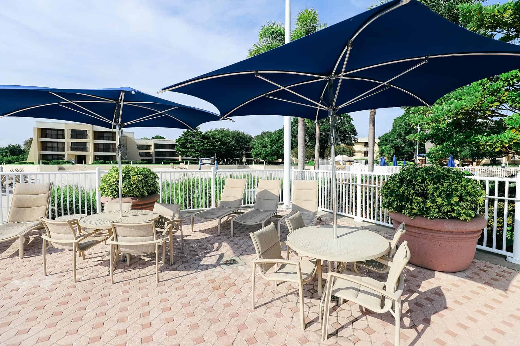 tables and chairs with umbrellas near the pool area 