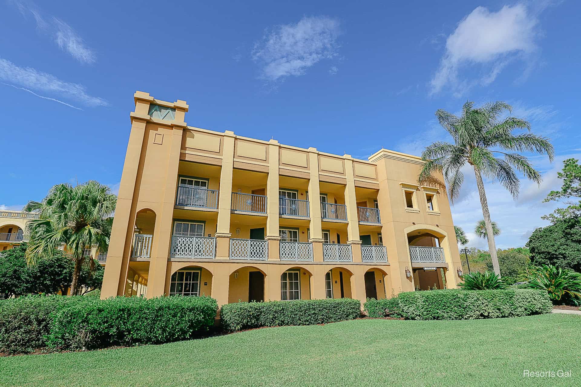 a building in the Casitas section with blue skies, green grass, and palm trees 