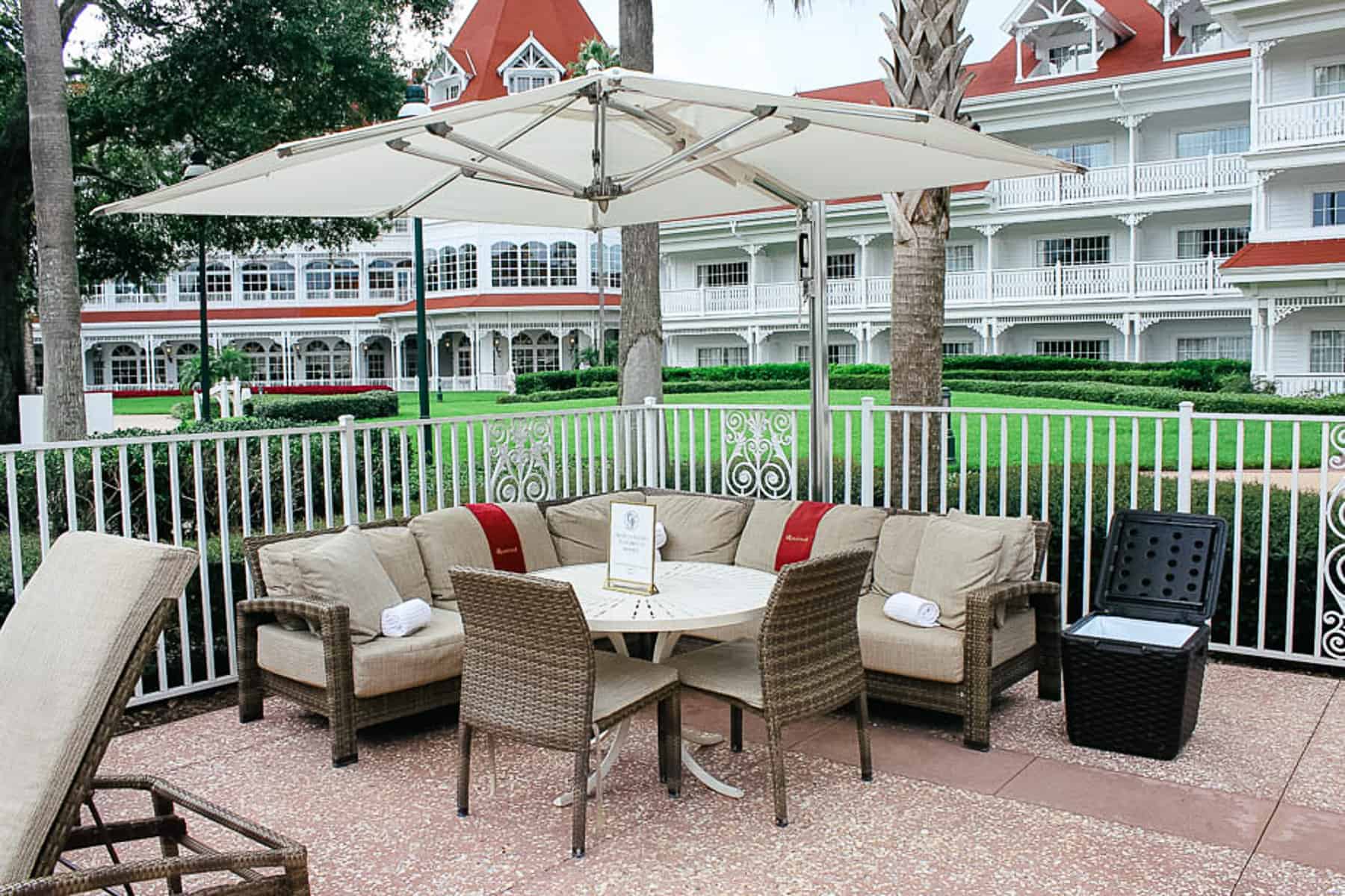 a cabana or poolside patio at the Courtyard Pool with a sectional sofa, table, and umbrella 