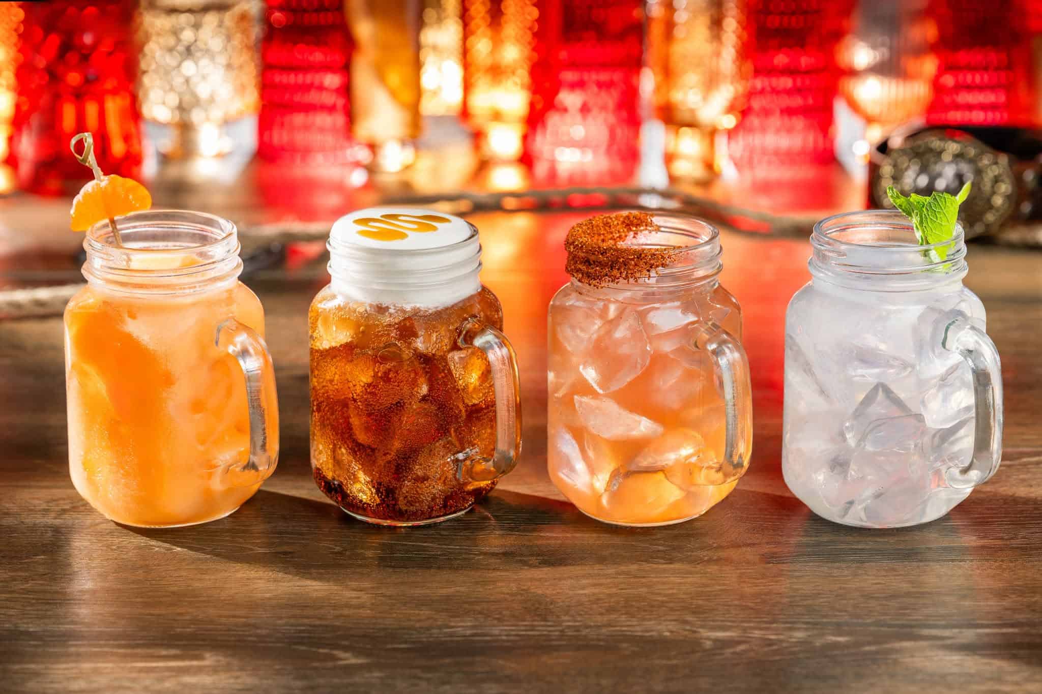 four beverages in Mason jars with handles coming to the Diamond Horseshoe
