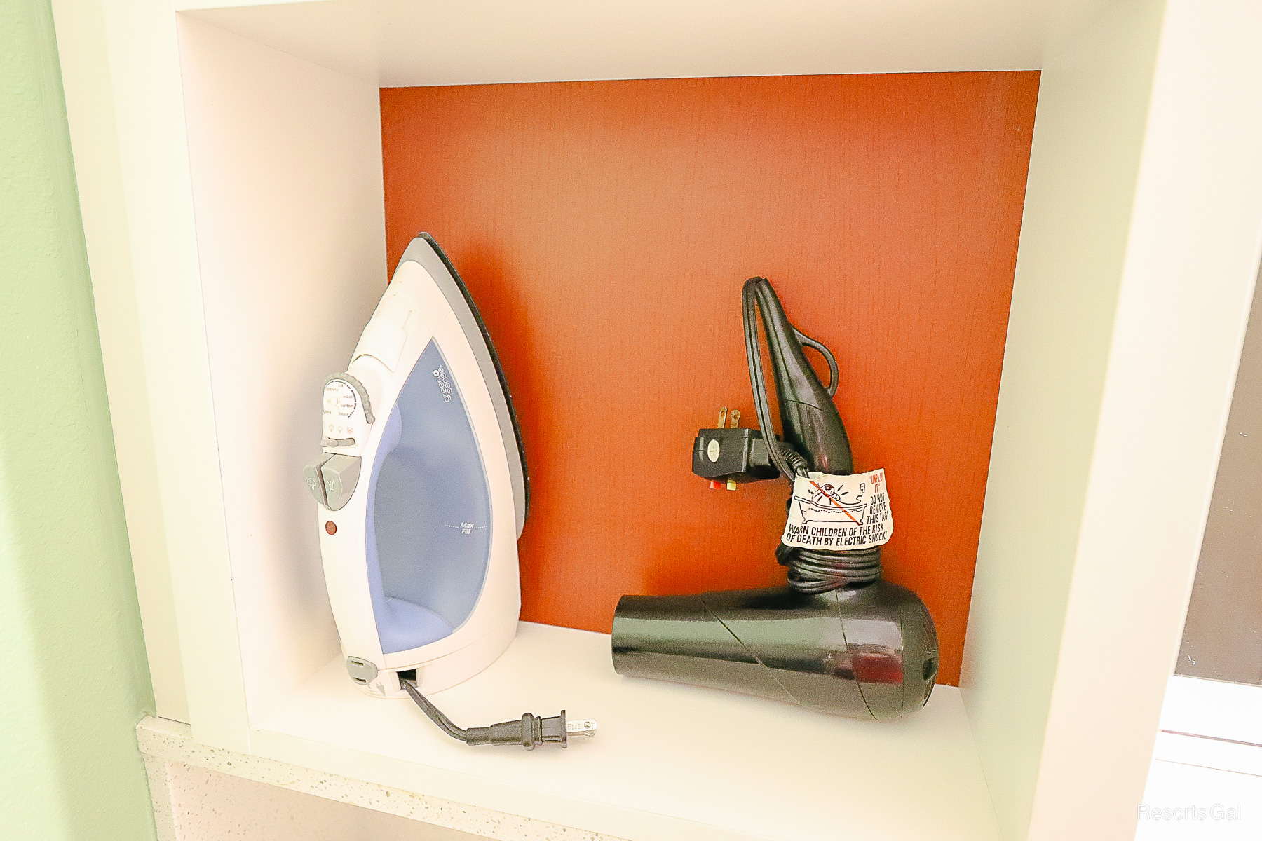 a cubby shelf with an iron and a hairdryer 