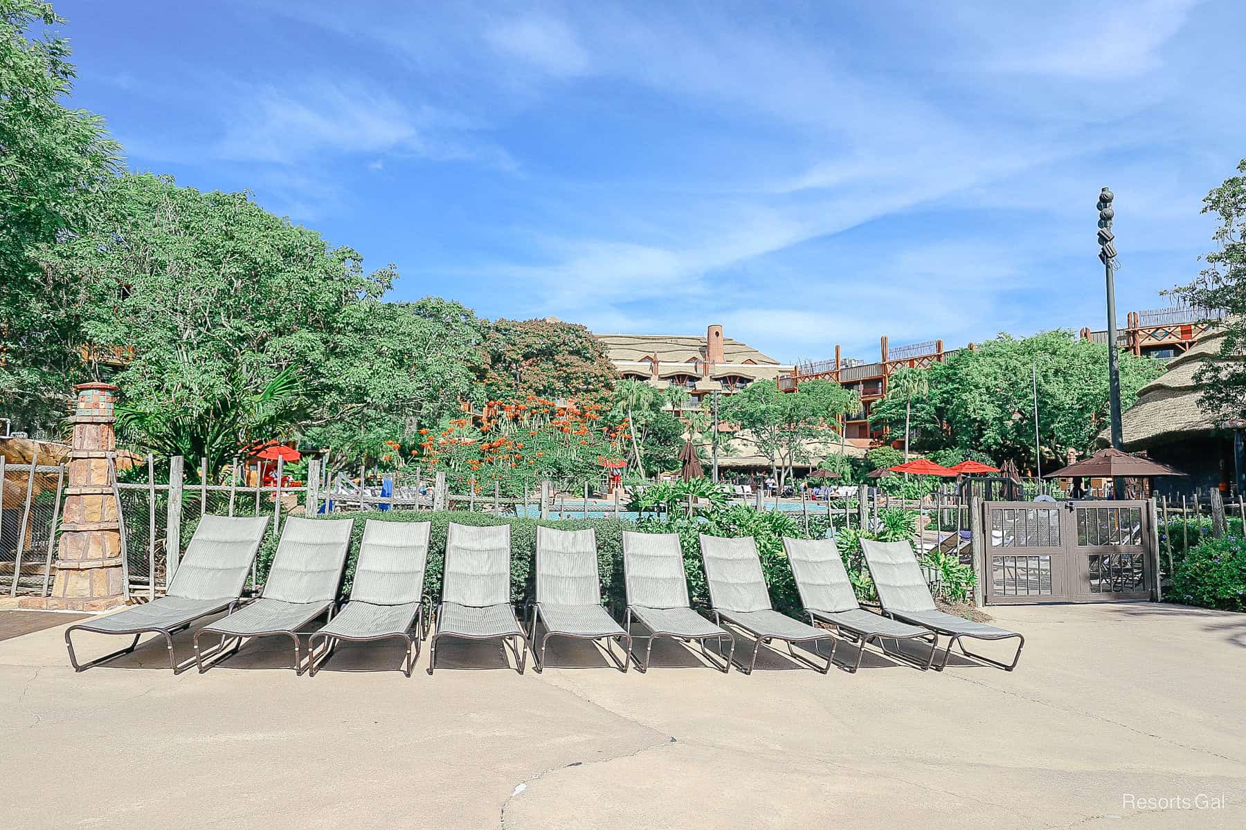 a row of lounge chairs sitting outside the pool area 