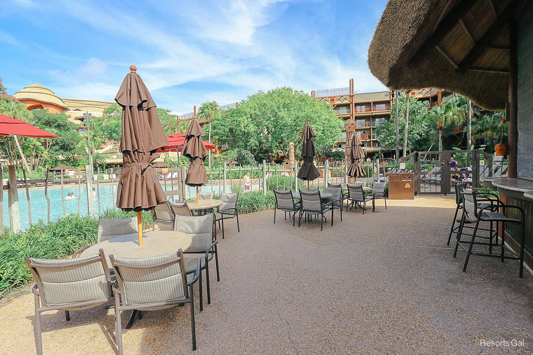 tables and chairs sitting around the pool bar 