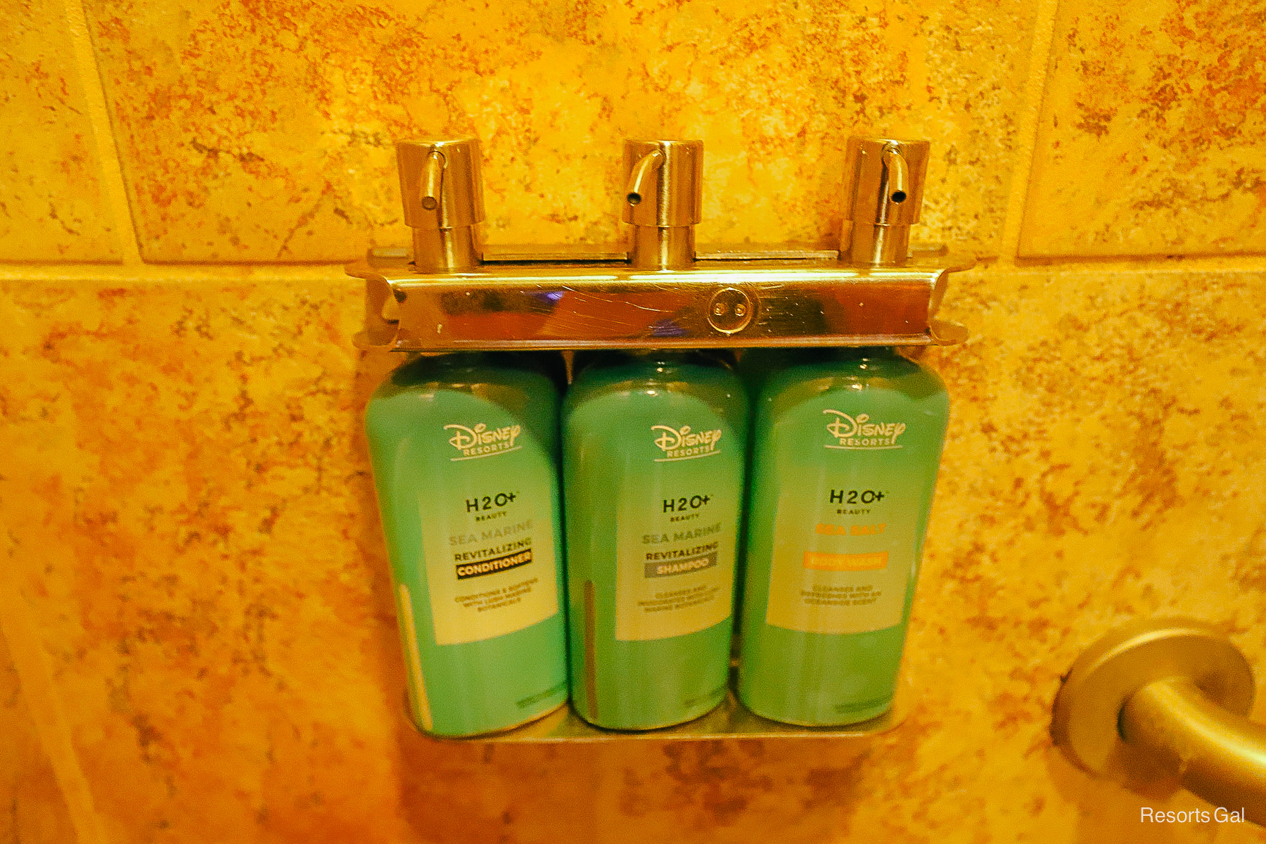 a bottle of conditioner, shampoo, and body wash in the pool shower 