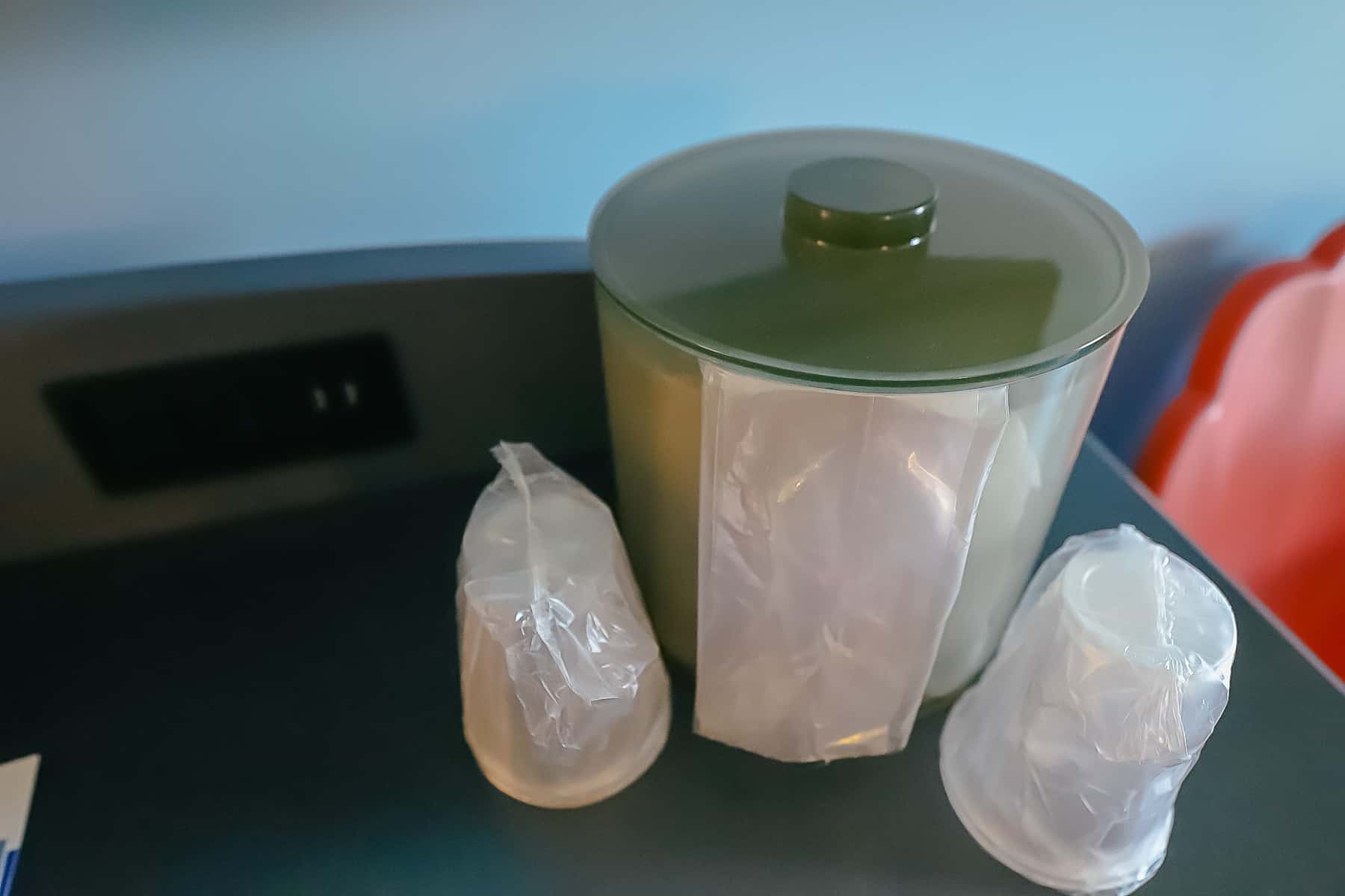 an ice bucket with plastic cups 