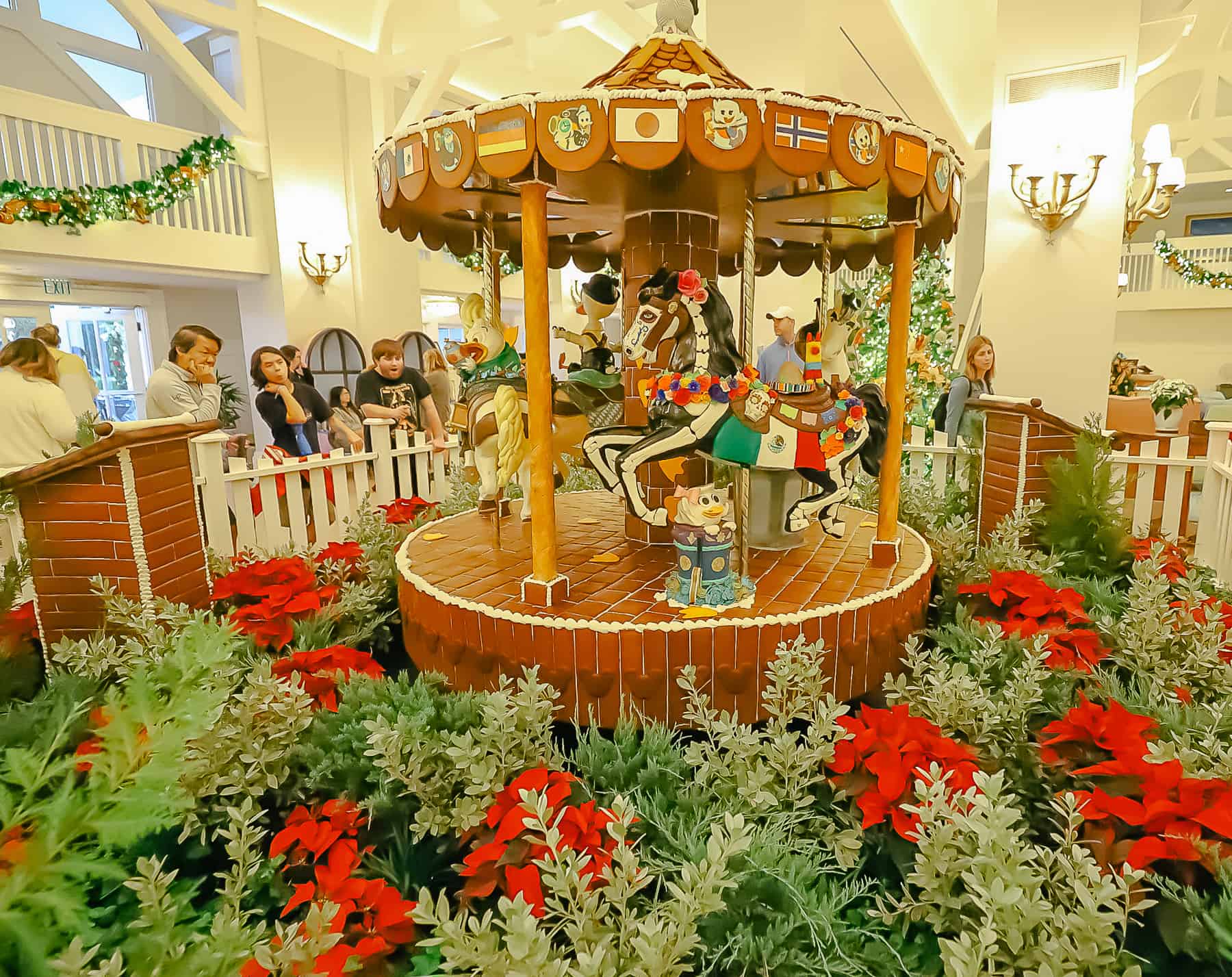 The 2023 gingerbread display is surrounded by greenery and poinsettias in the Beach Club's lobby. 