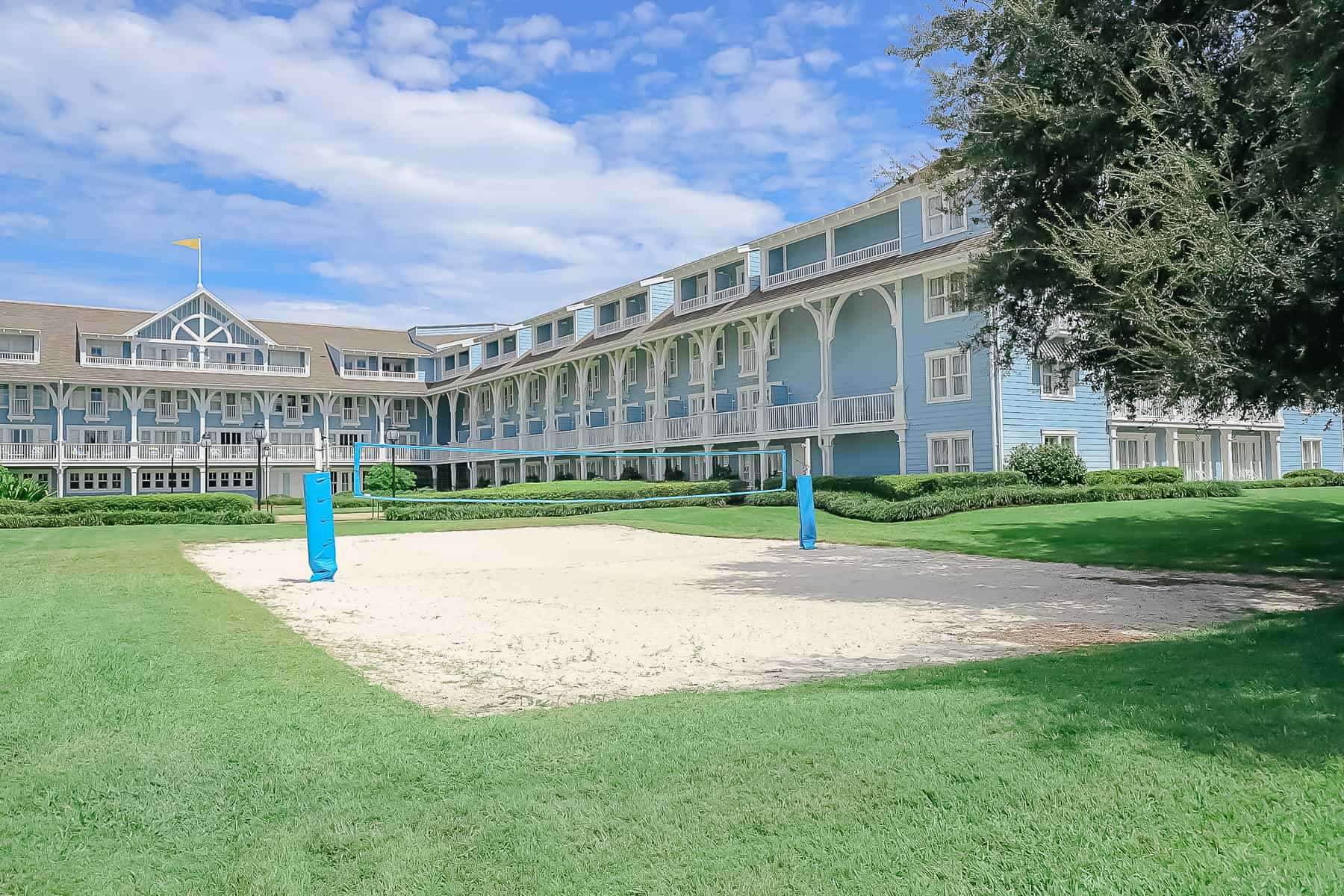 a sand volleyball court in front of the blue Beach Club with white trim 