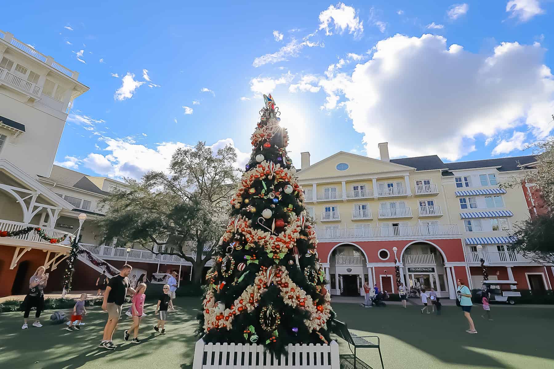 shows lots of families admiring the Christmas tree on the lawn at Disney's Boardwalk