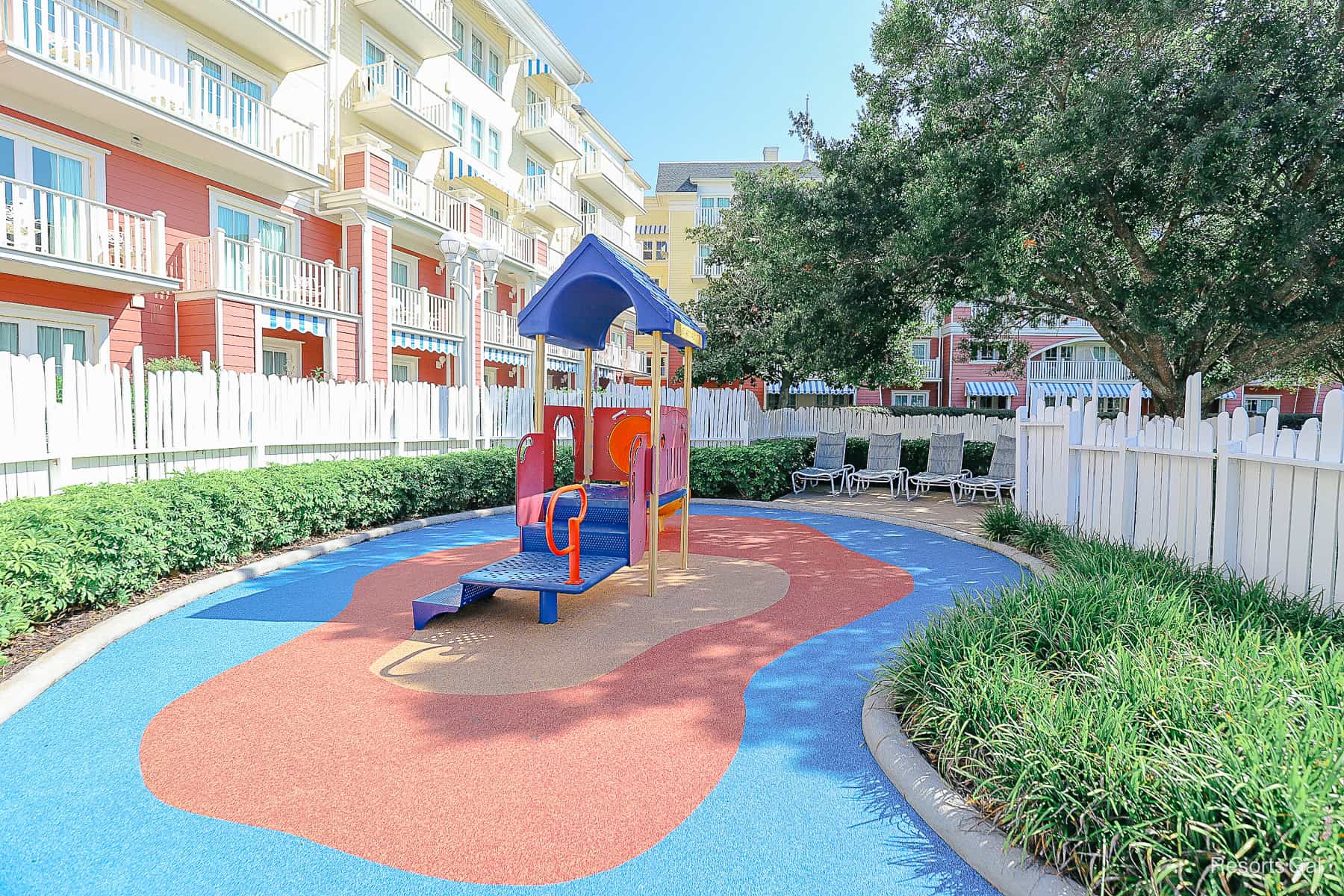 shows the cork or rubber flooring of the playground surrounded by a white fence