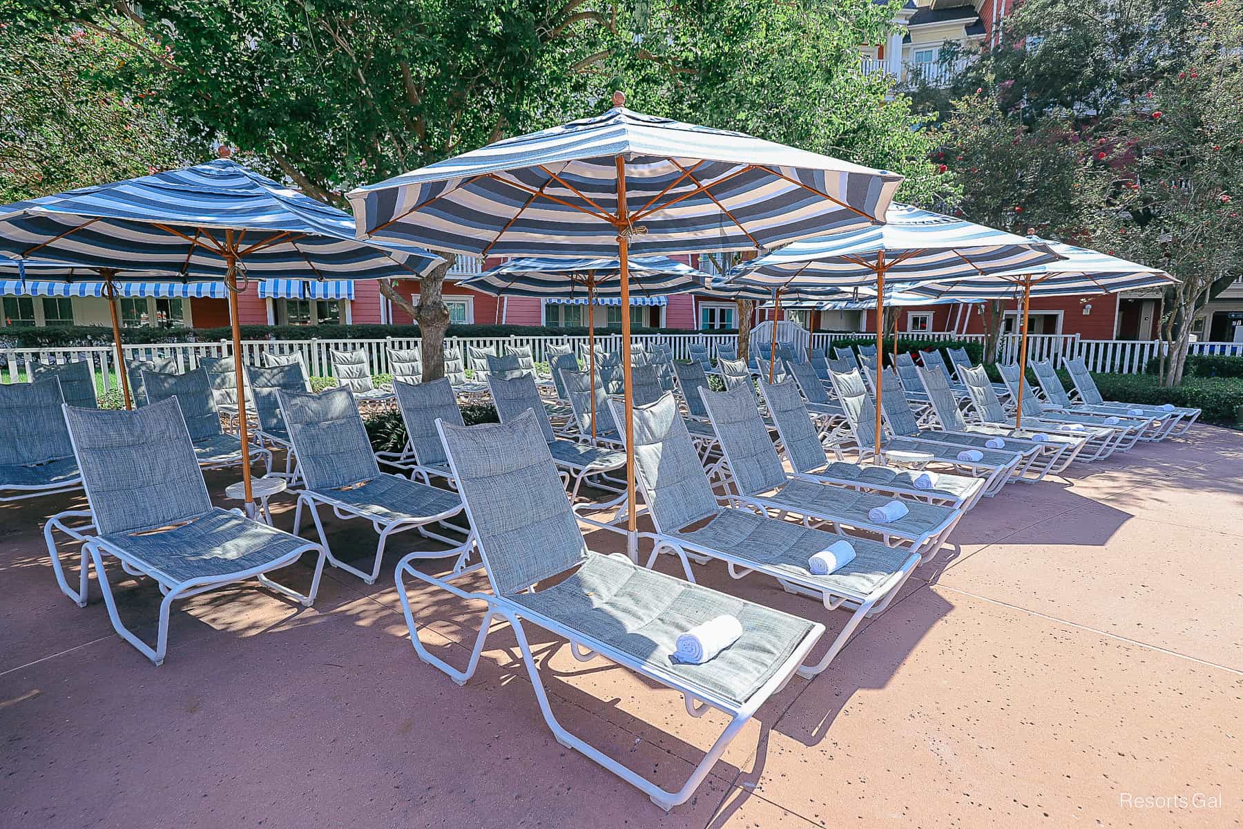 four rows of lounge chairs with umbrellas in a shaded area near the Boardwalk pool 
