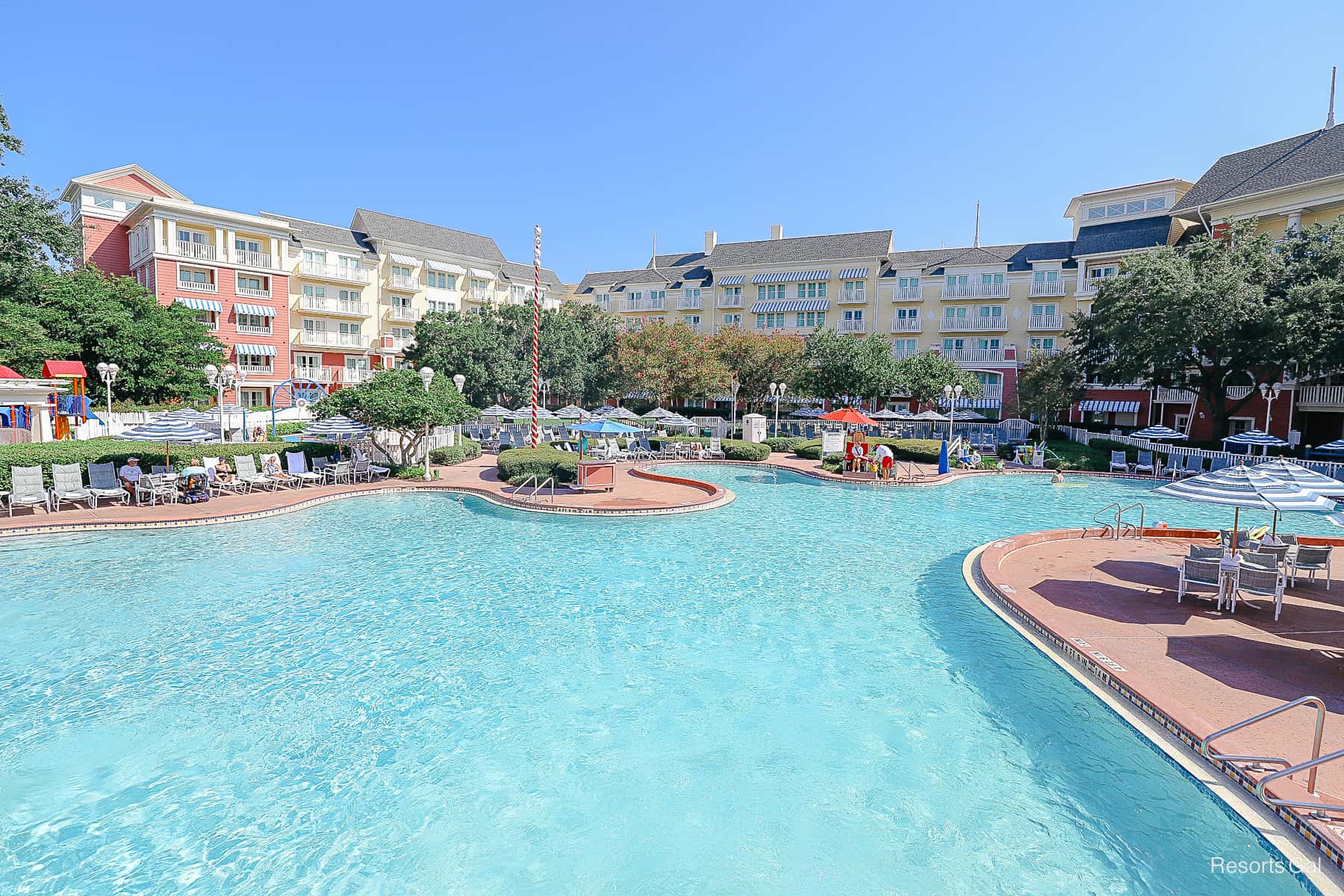 the blue waters of the pool with the yellows and red of Disney's Boardwalk Inn in the background 