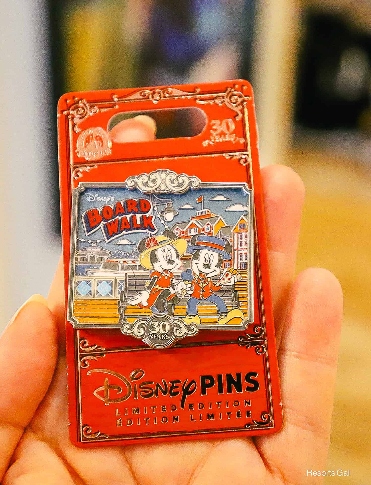 the pin features Mickey and Minnie Mouse sitting on a bench at the Boardwalk 