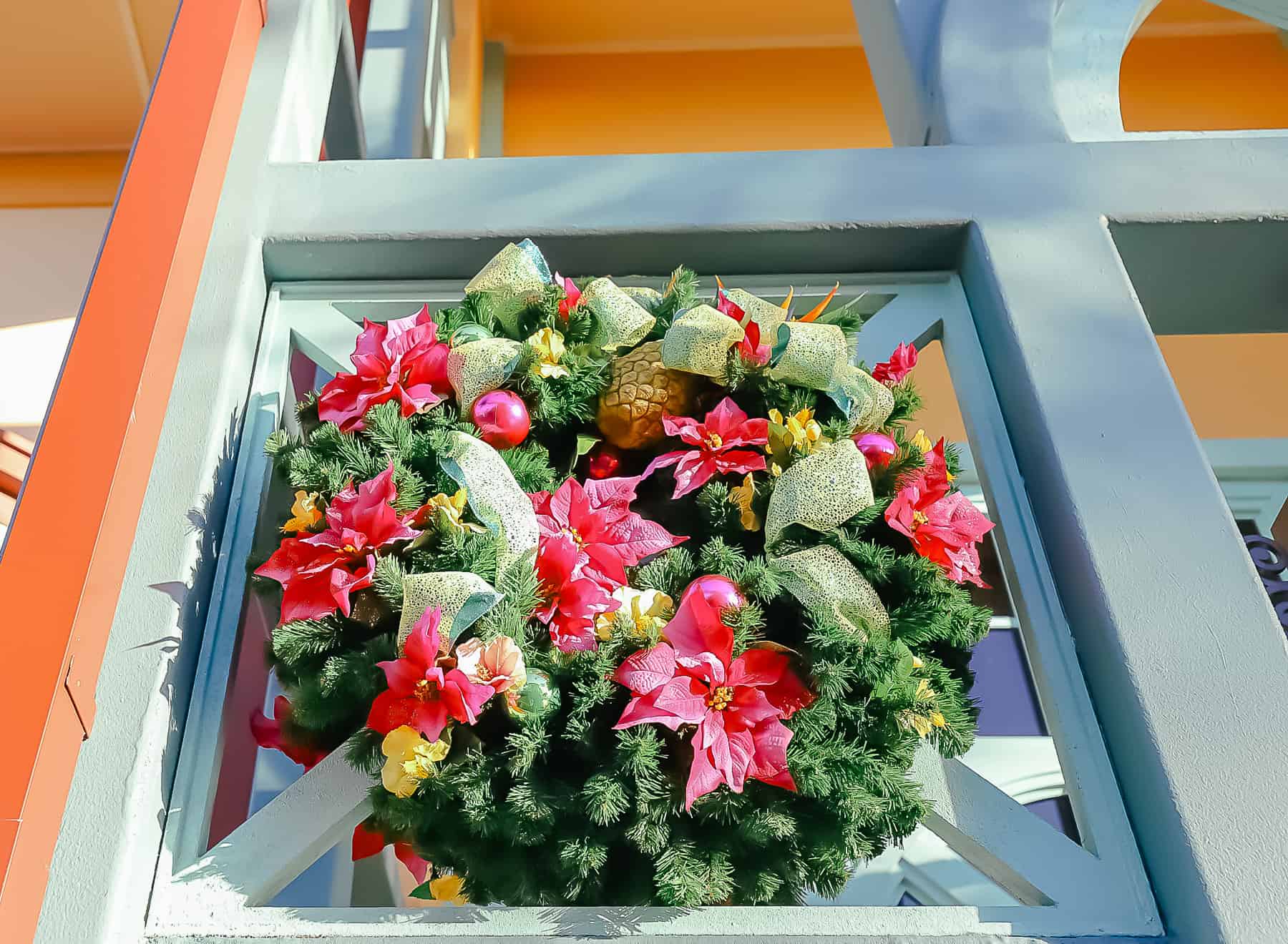 A close up of an outdoor Christmas wreath with pineapples and hot pink poinsettias. 