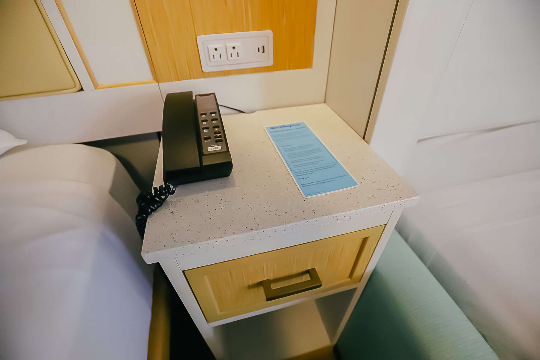 a nightstand with a phone, outlets, USB ports, and a drawer