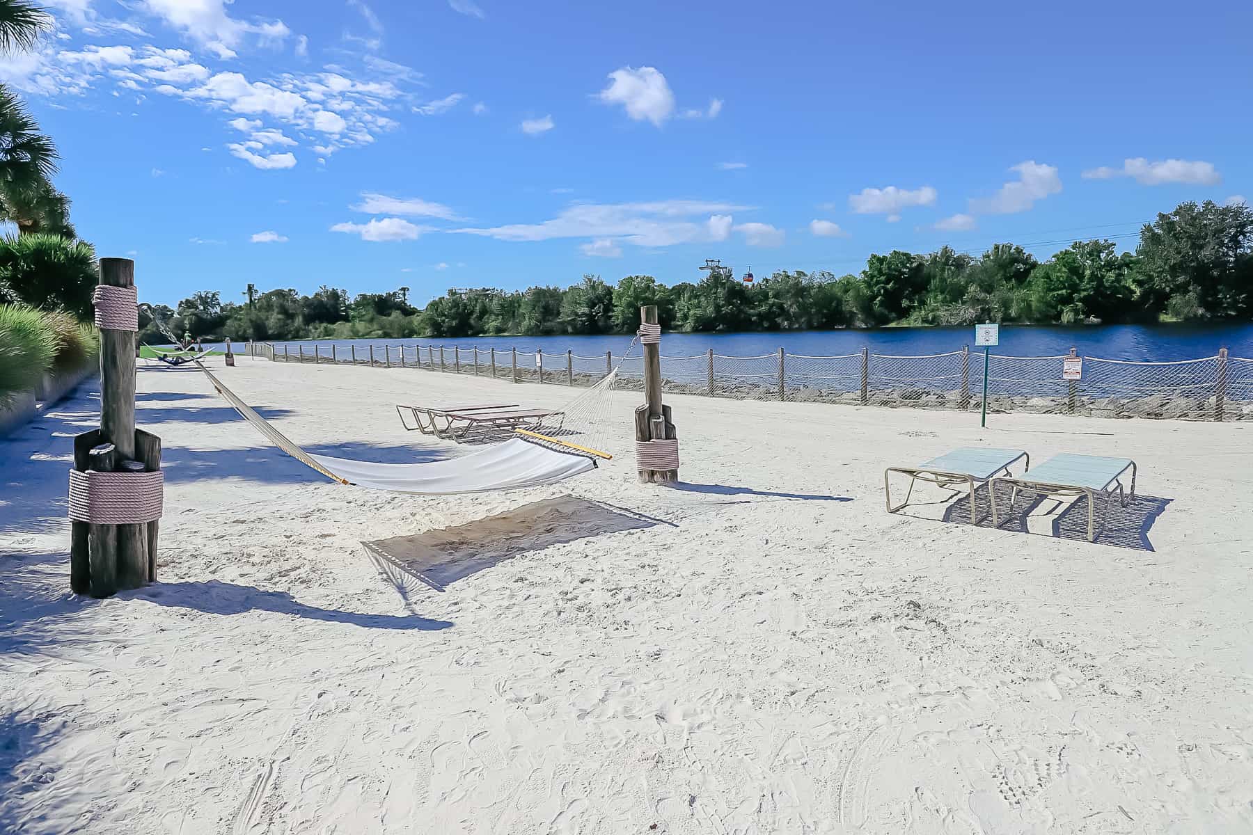 sandy beach with lounge chairs and a hammock 