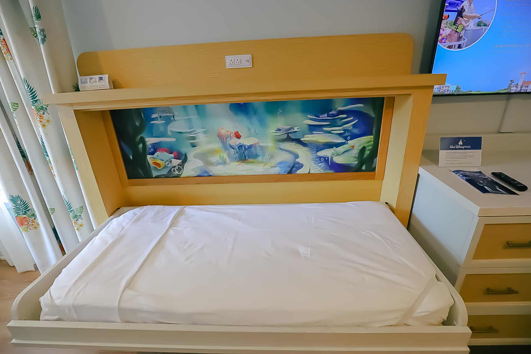 single pull down bed with Little Mermaid artwork behind it
