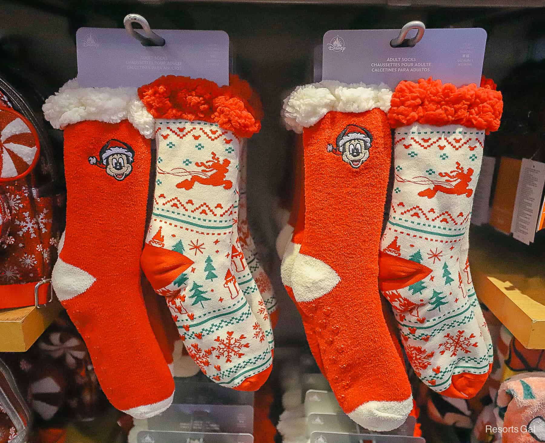a pair of adult socks with holiday designs. One is red with Mickey Mouse and the other is white with a Disney print. 