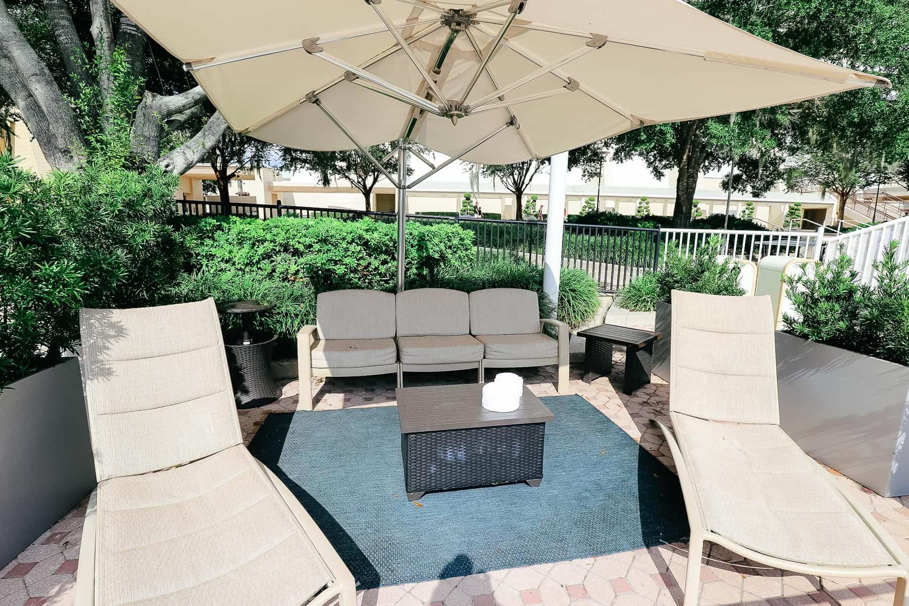 a private cabana rental with two lounge chairs, a couch, and an umbrella at Disney's Contemporary 