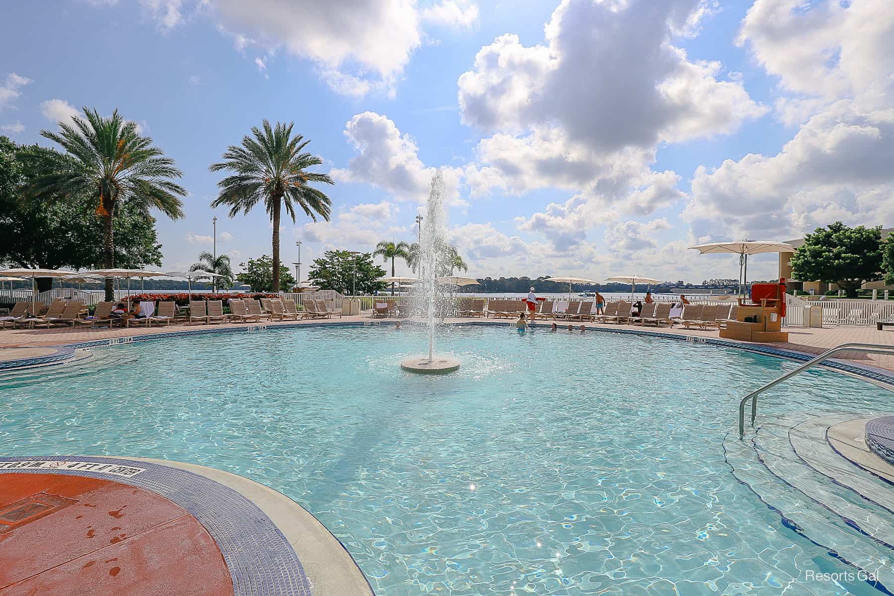 a pool at Disney's Contemporary Resort with a fountain water feature in the center and a lake in the background