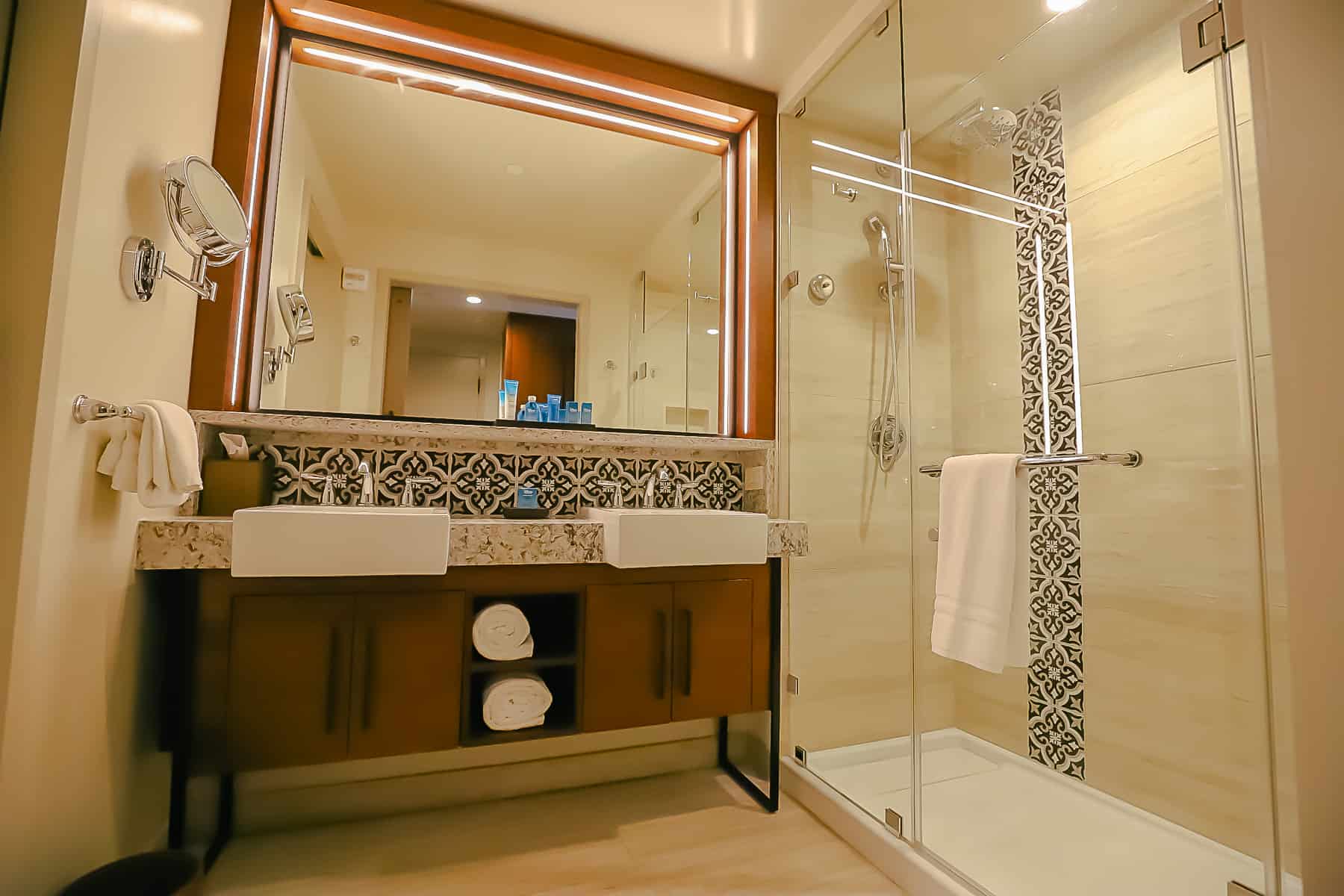 guest bath showing storage space, two sinks, and shower