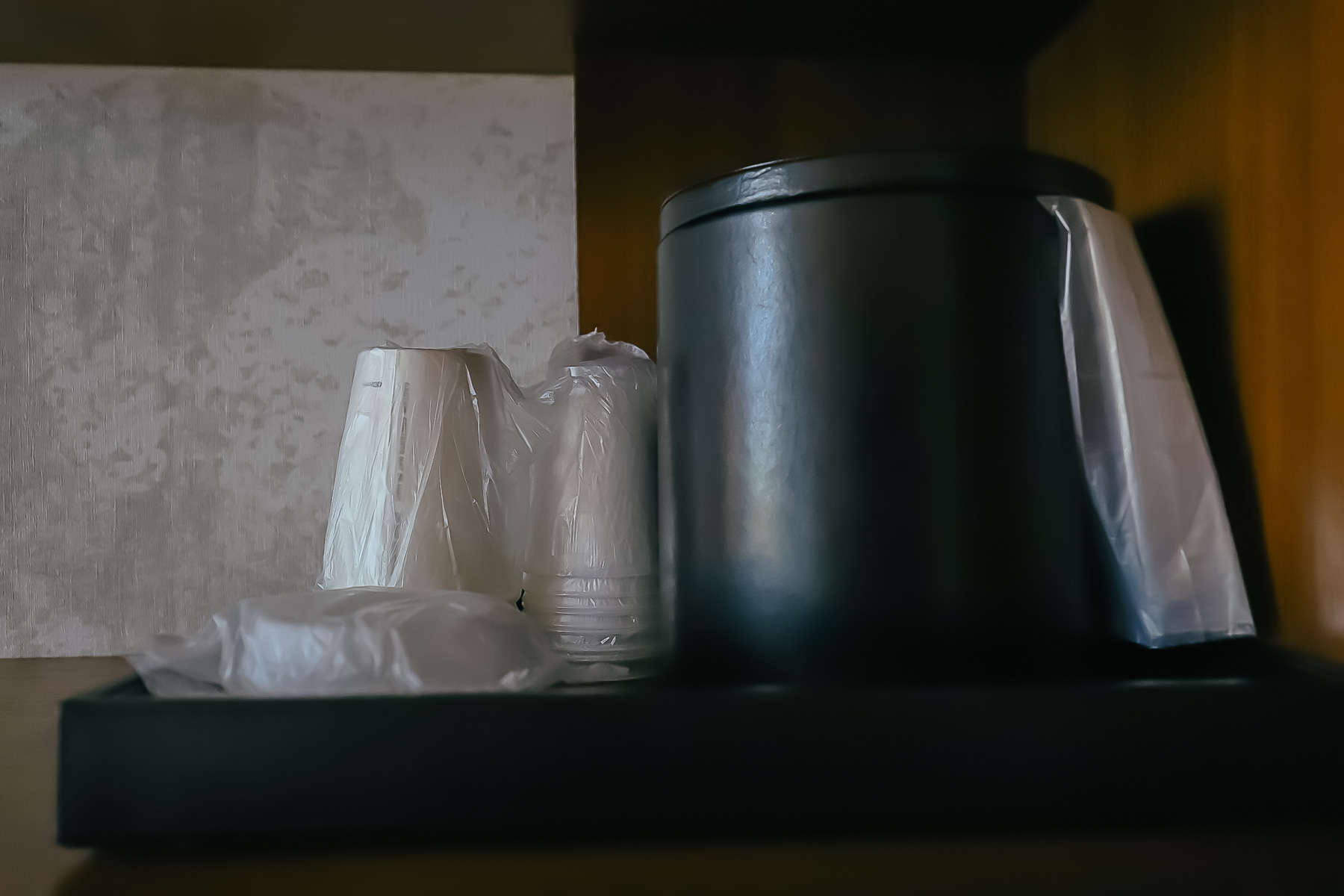 a hotel room ice bucket with plastic cups 