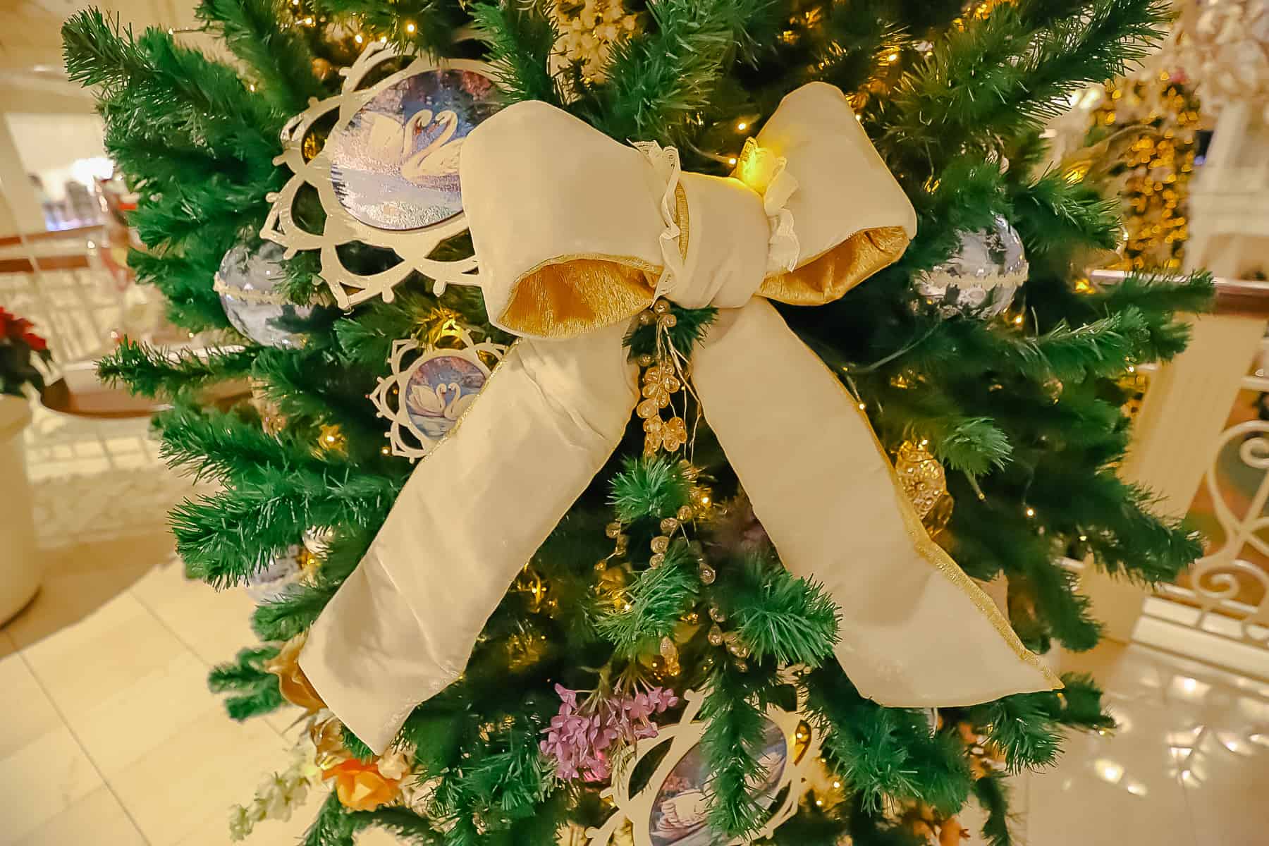 A large white bow with gold trim pinned to the tree. 
