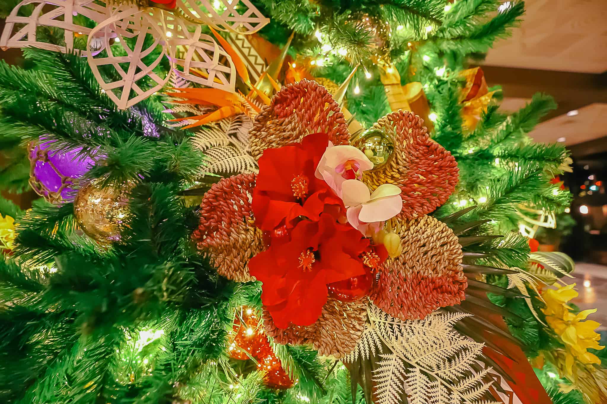 An ornament that's shaped like a flower with faux tropical flowers on it. 