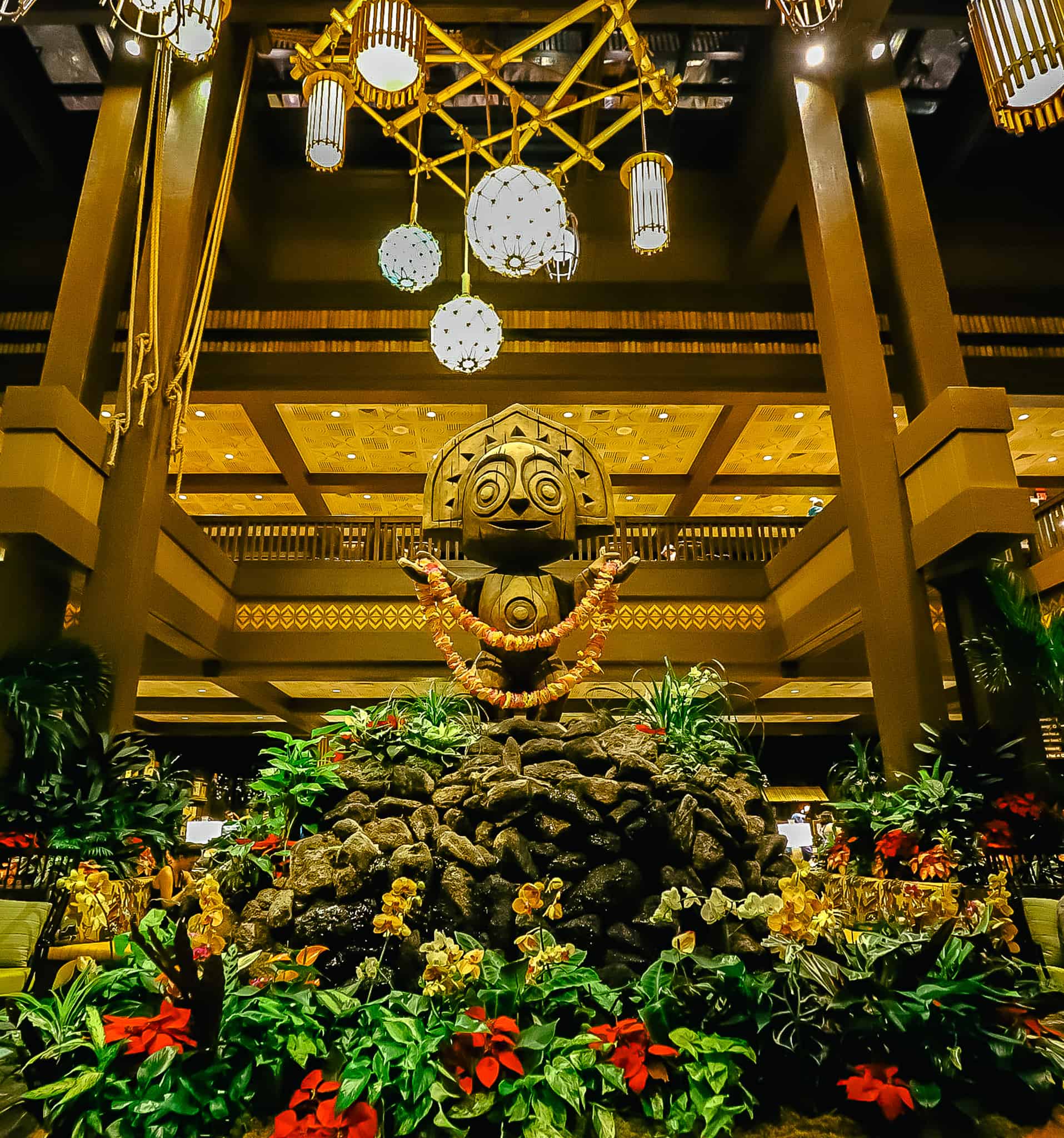 A tiki man statue in the lobby of the Polynesian that's surrounded by poinsettias during Christmas. 