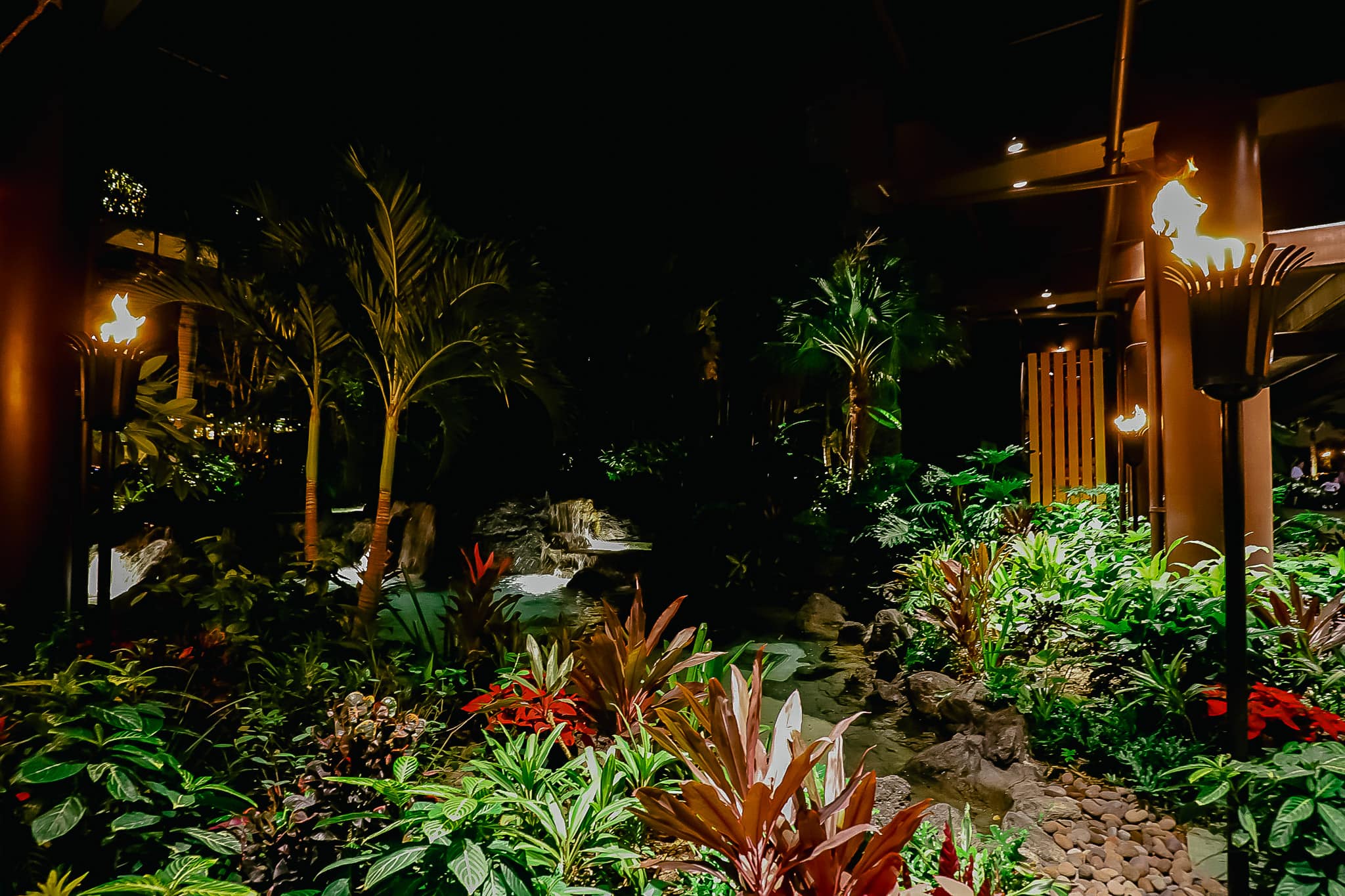 The landscape at the Polynesian around Christmas with Tiki torches burning at night. 