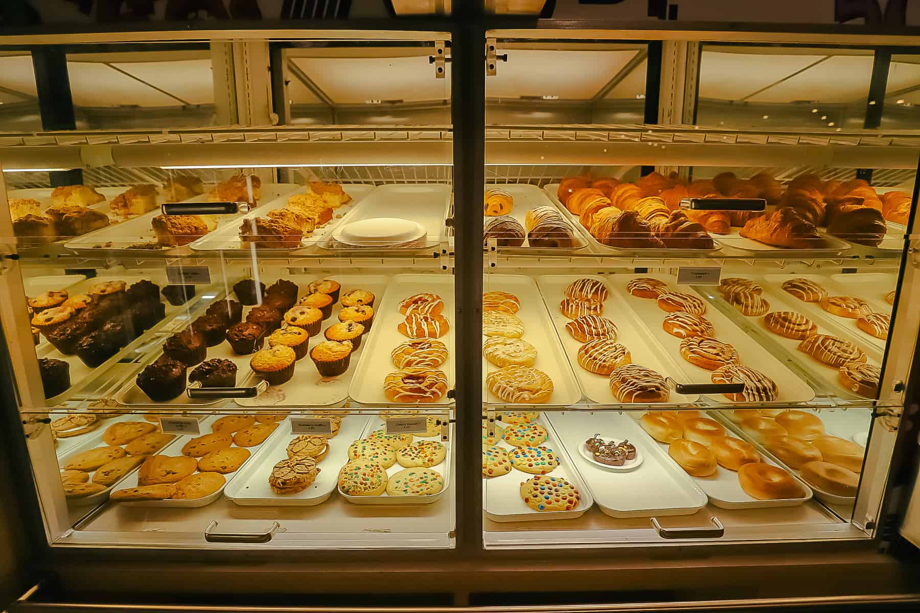 pastry case with croissants, cinnamon rolls, donuts, muffins, and cookies 
