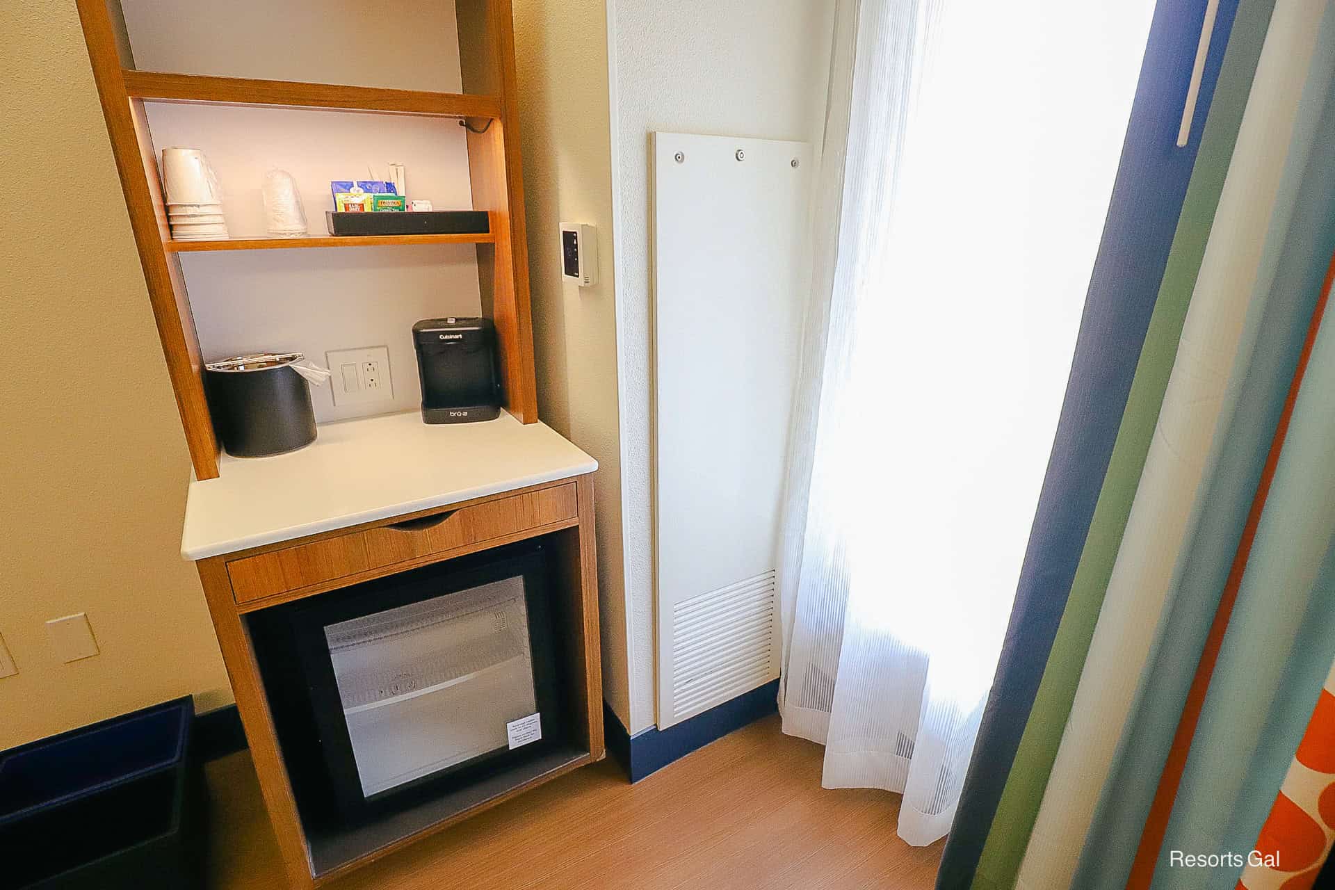 a stand in the corner of the room for beverages and food items 
