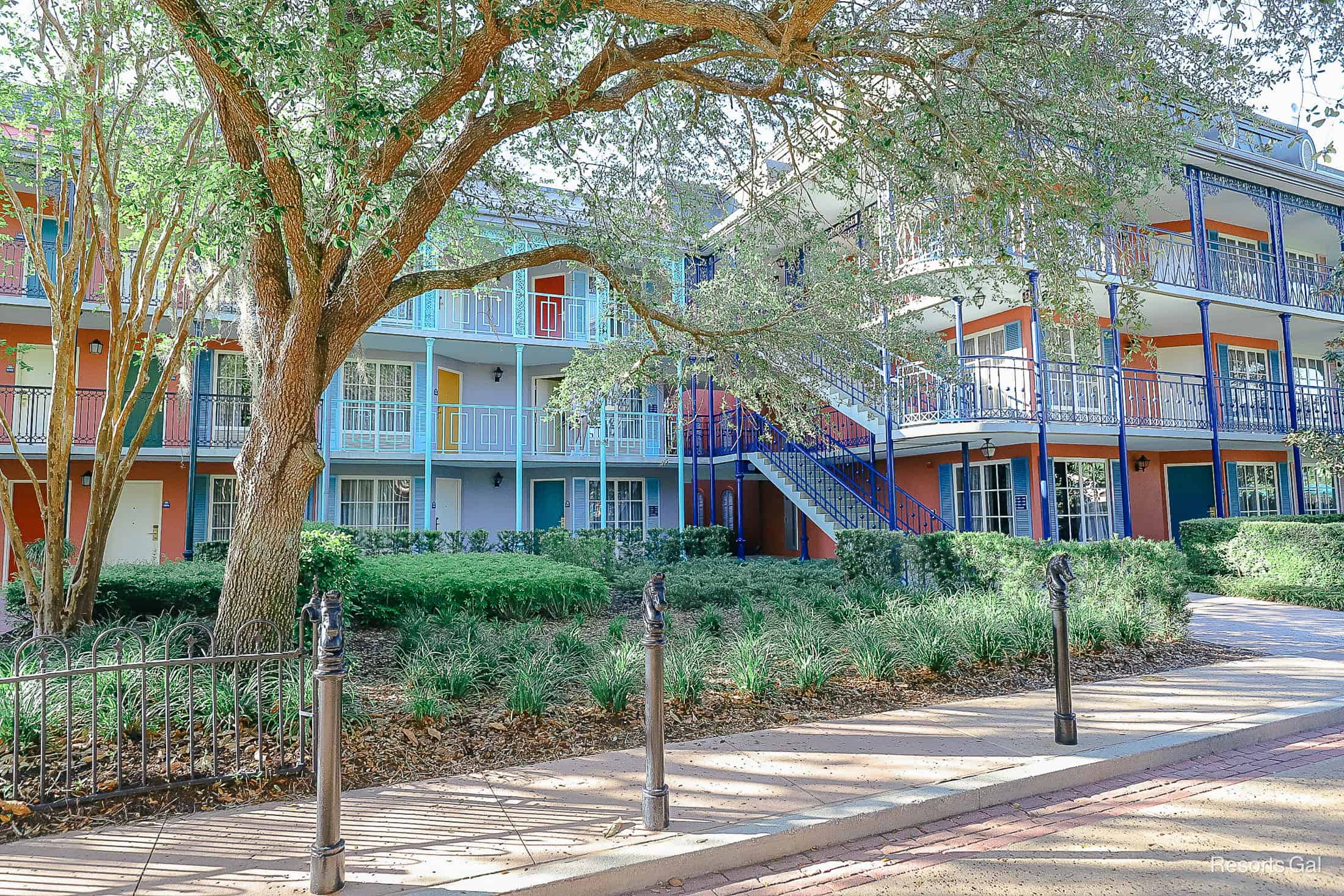 a tree in front of a set of buildings with light blues and pinks 