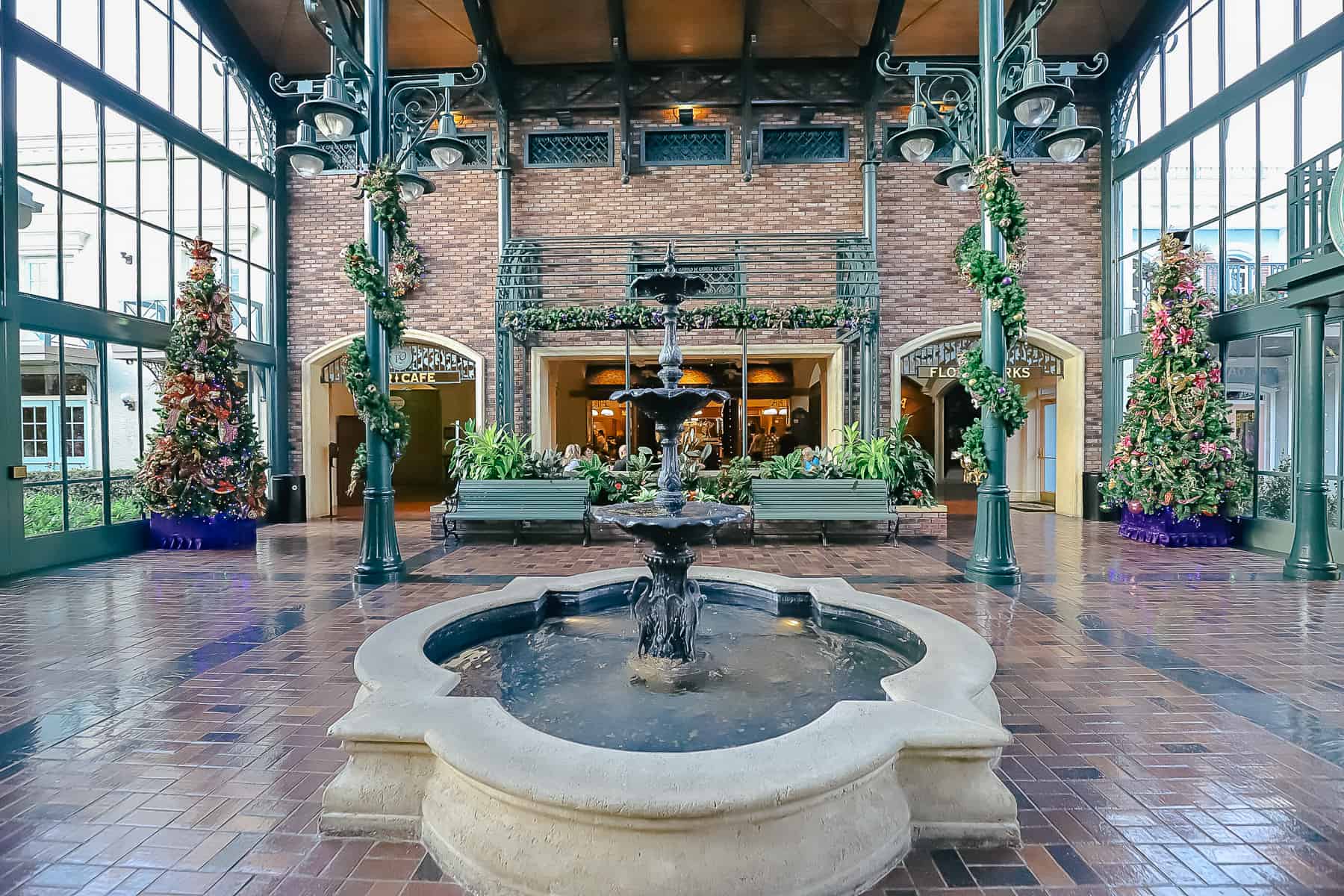A fountain in the center of the lobby with garland wrapped around the columns.  