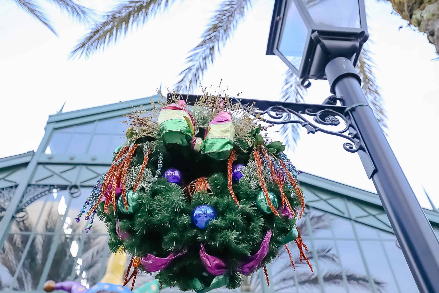 Wreaths hanging from a light pole with large bows. 