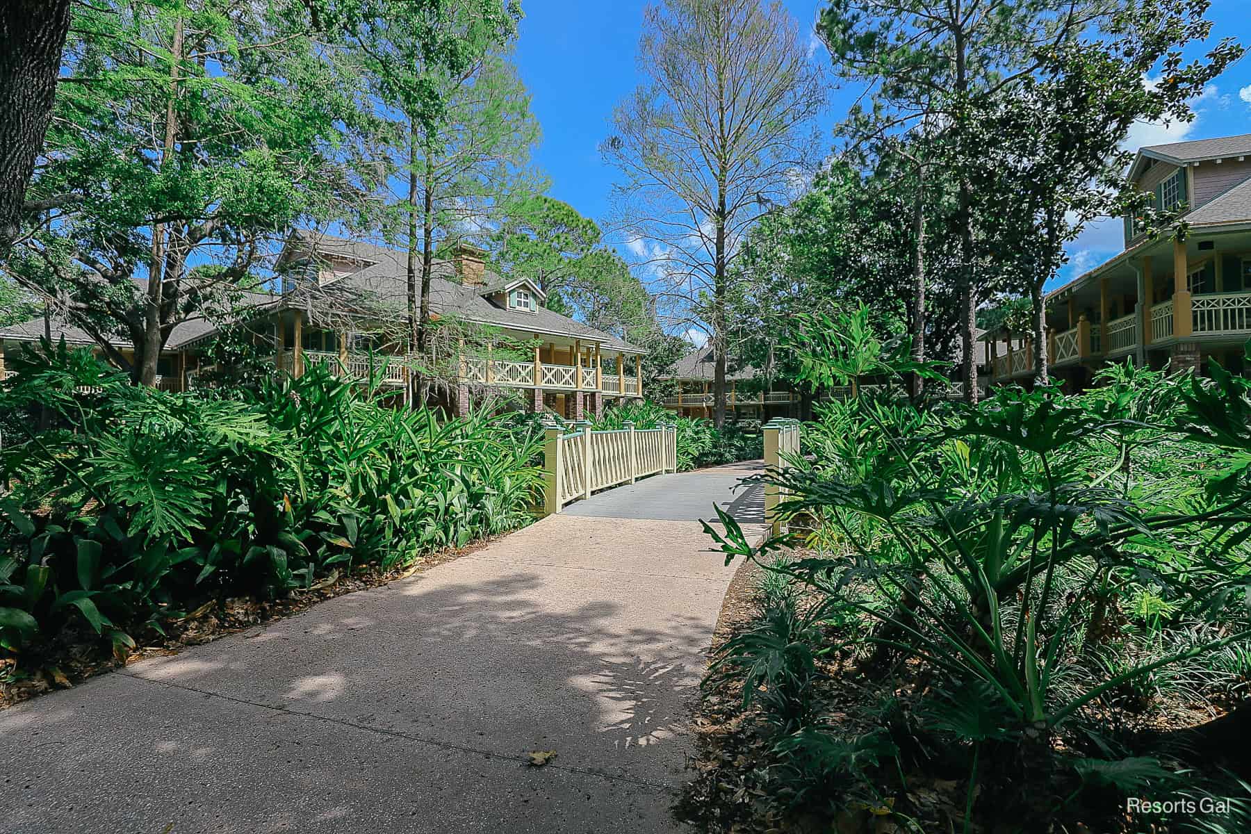 a small footbridge with landscaping and buildings in the backdrop 