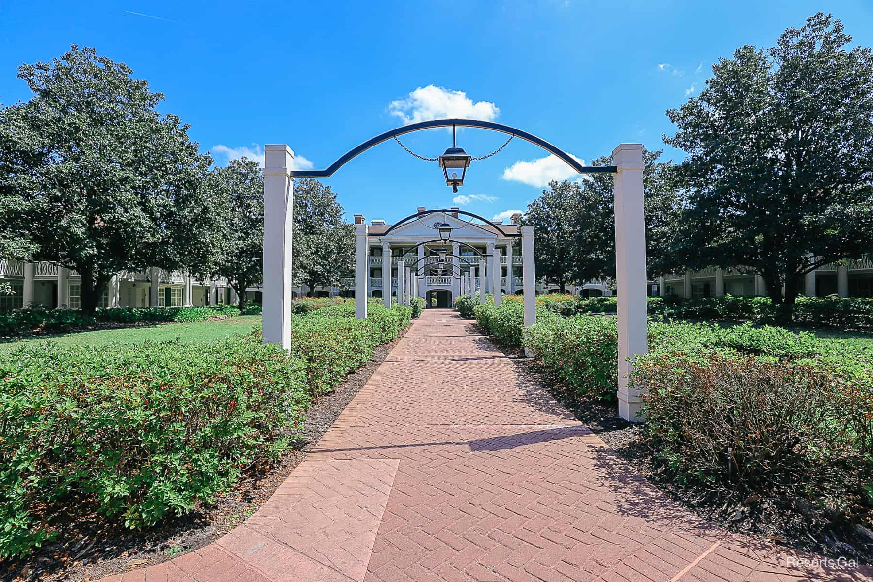 a long row leading up to a mansion with lights hanging from each arch 