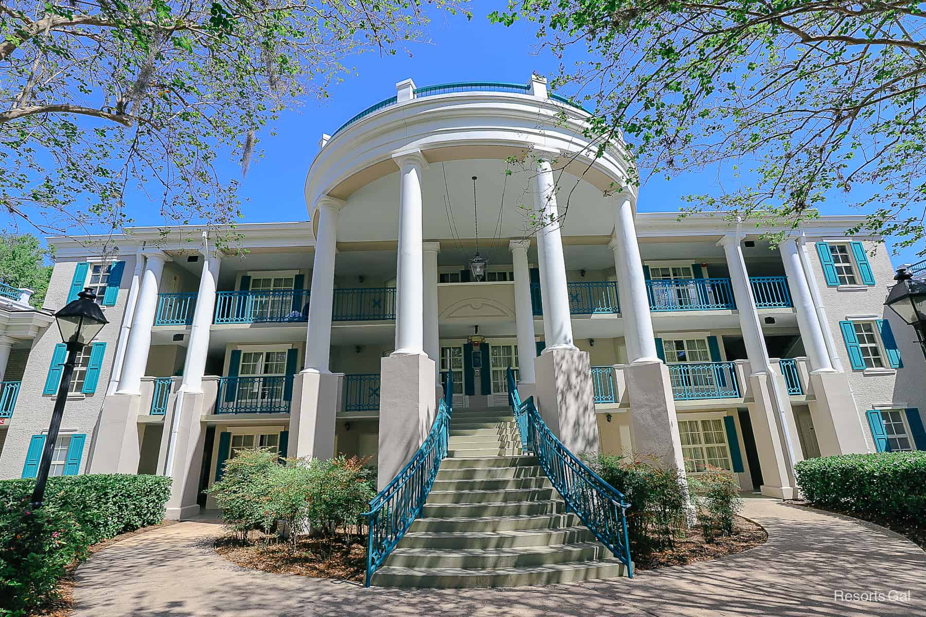 a white mansion building with large columns and turquoise trim 