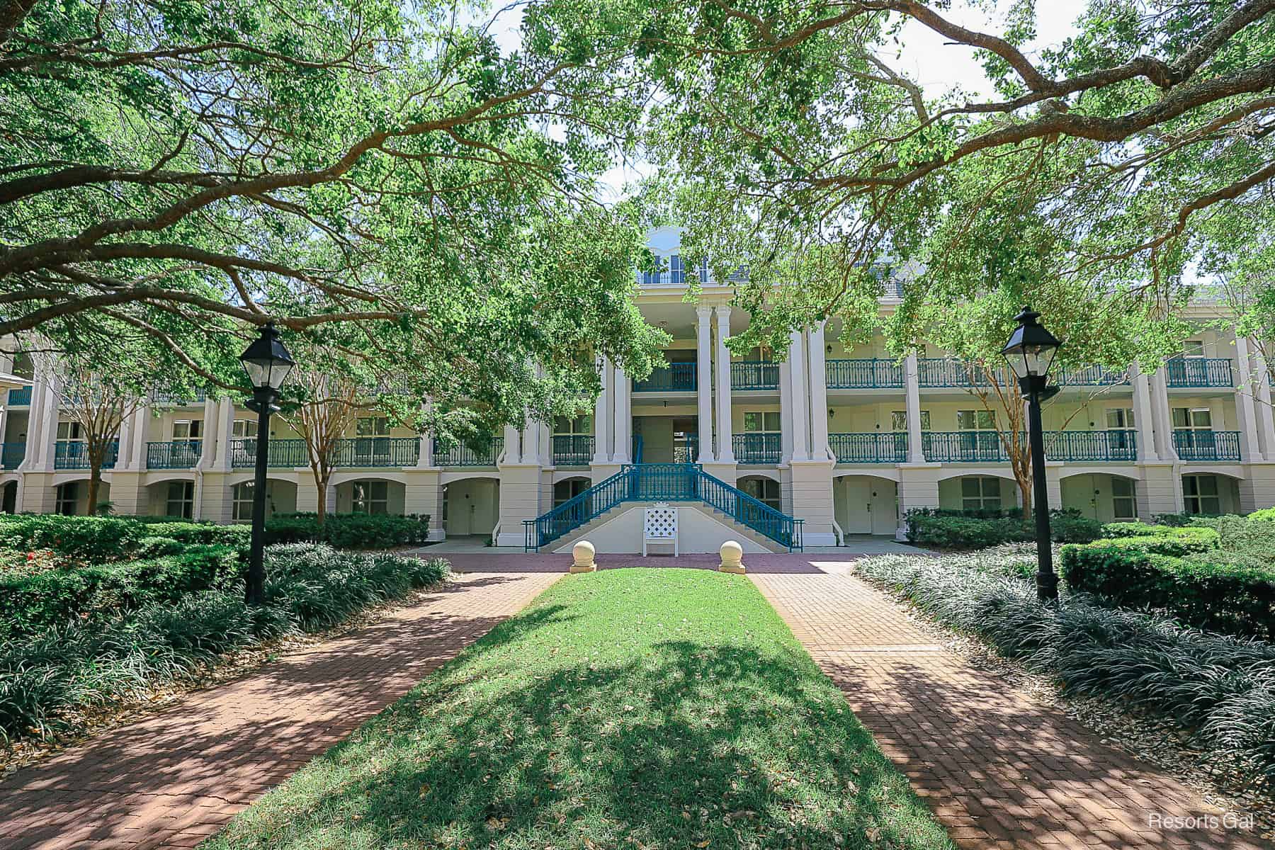 the mansions surrounded by trees and a long row of grass between brick pavers 