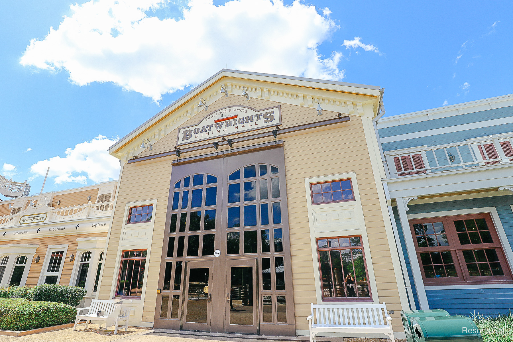 Boatwrights is a tall two-story building with tan paint and brown trim with red accents 