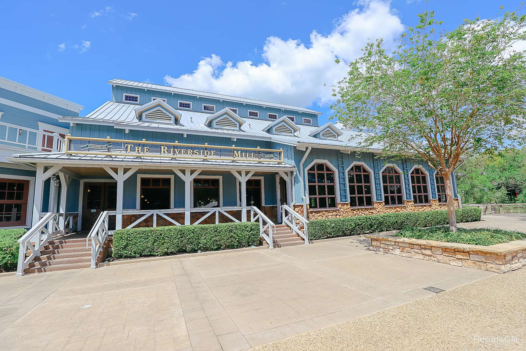 the Riverside Mill, a bright blue building with brown, white, and gold trim 