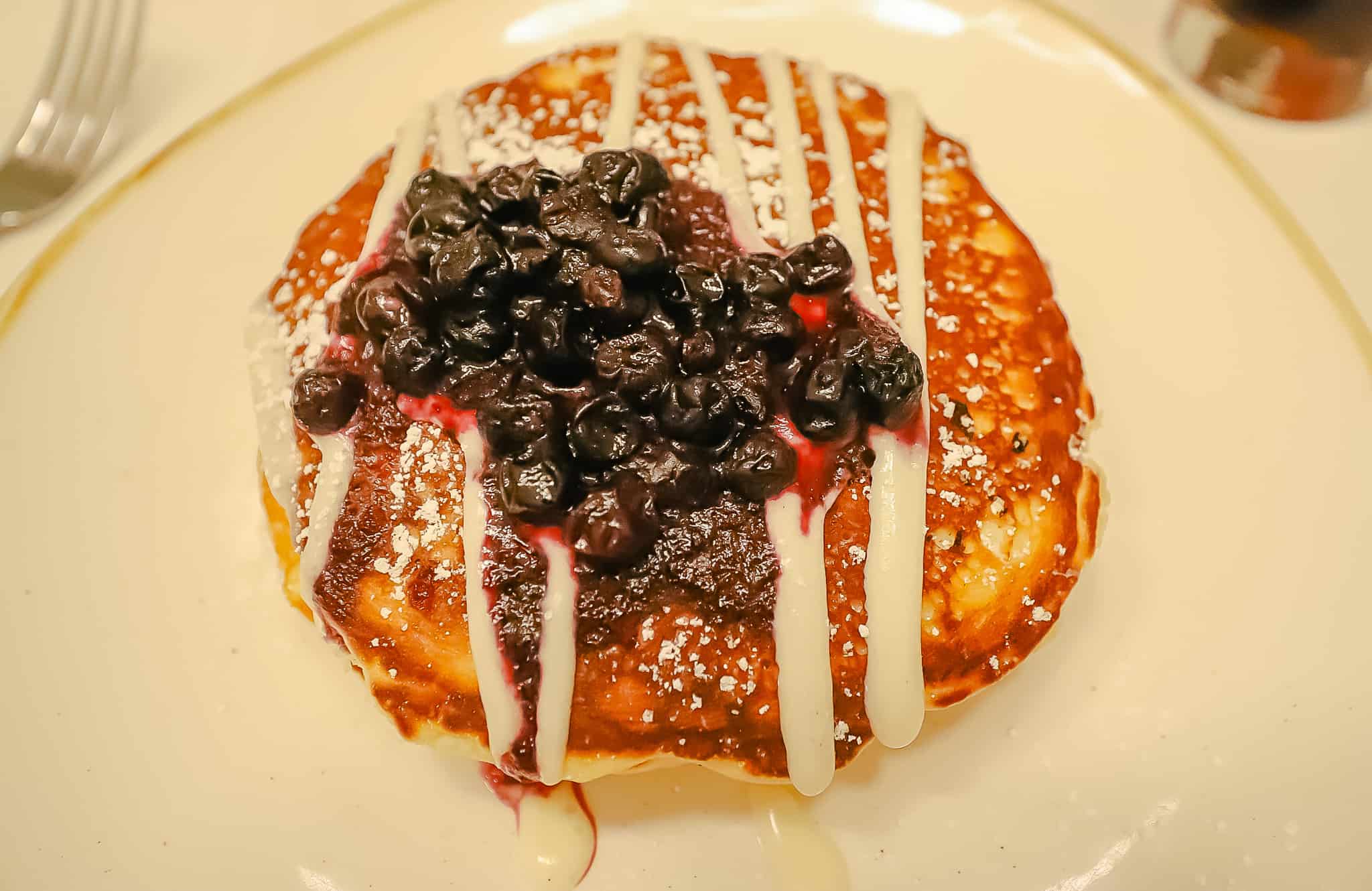 pancakes toped with a sugar drizzle and blueberries 