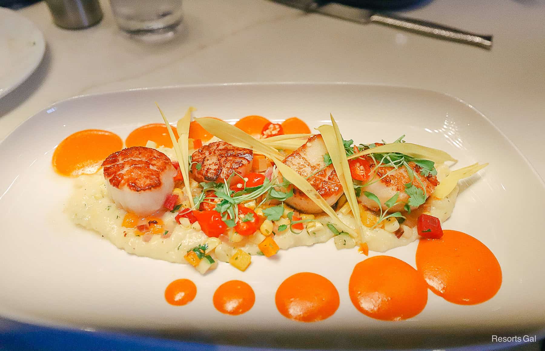 an order of scallops with an orange pepper sauce drizzled on each side