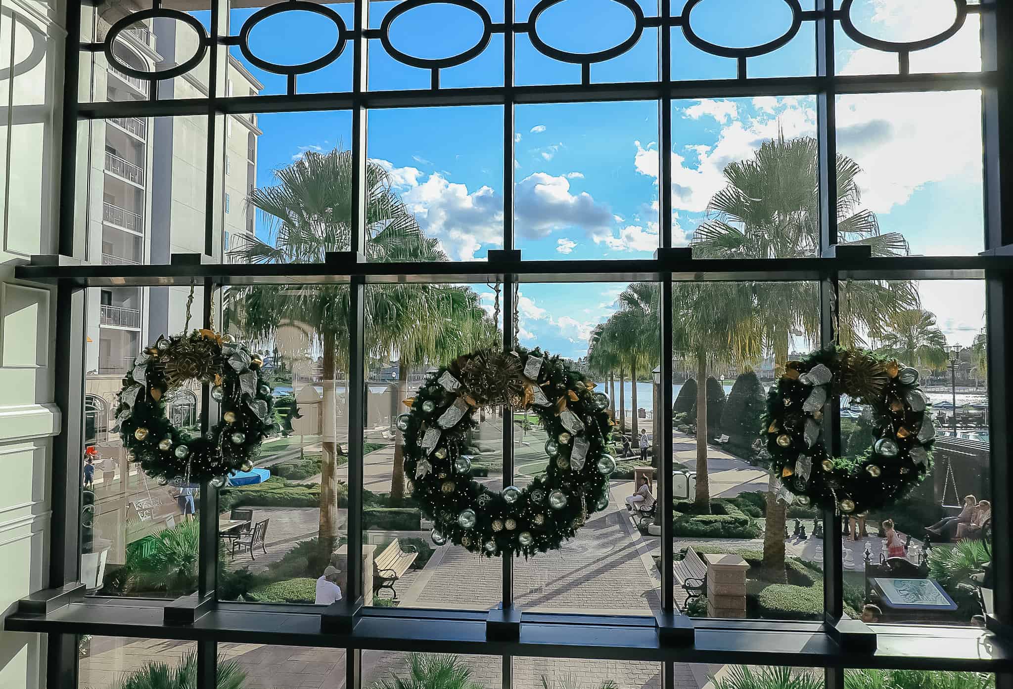 Three wreaths hanging in the lobby window of Disney's Riviera Resort. 