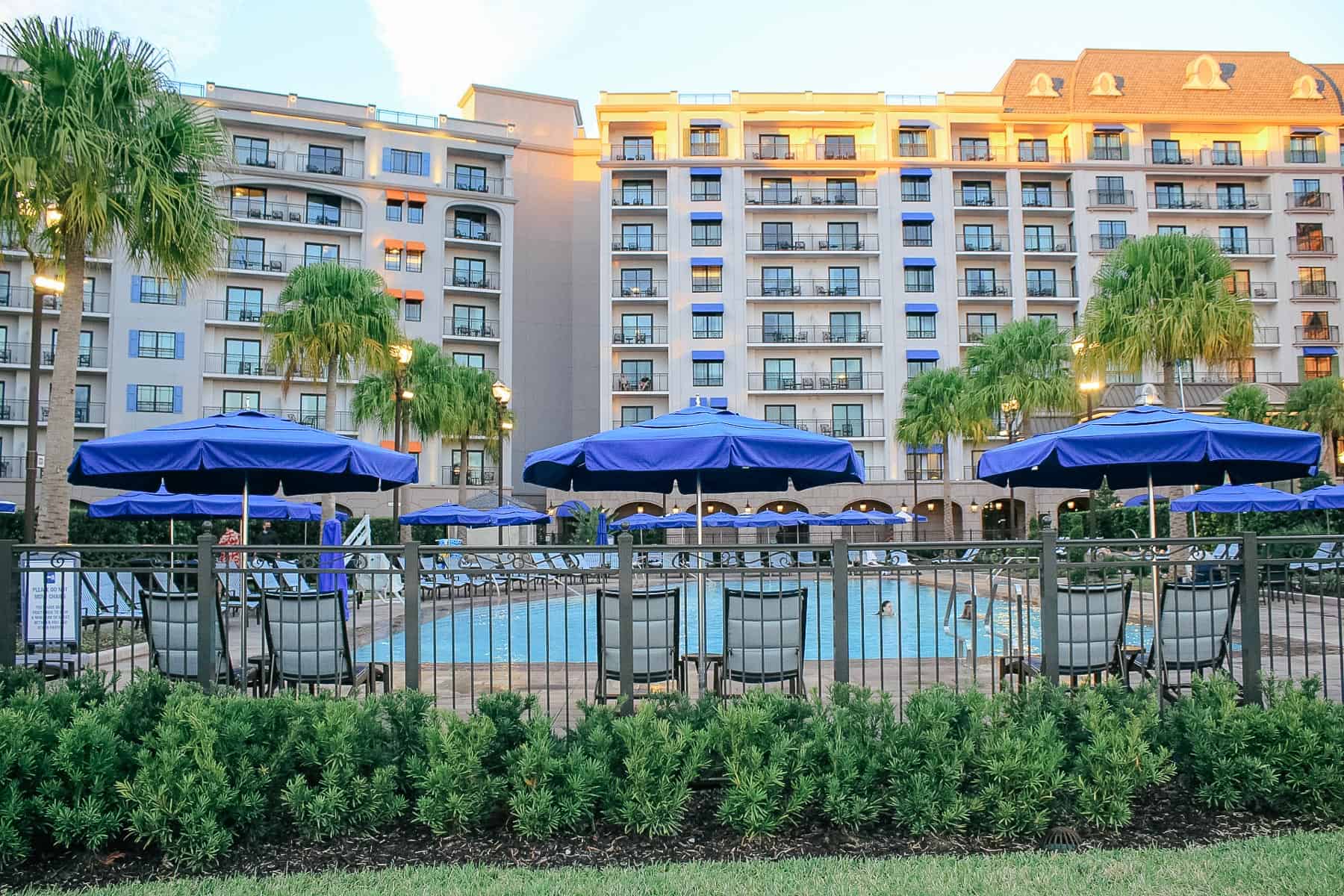 the sun shining on Disney's Riviera in the backdrop with the pool toward the front 