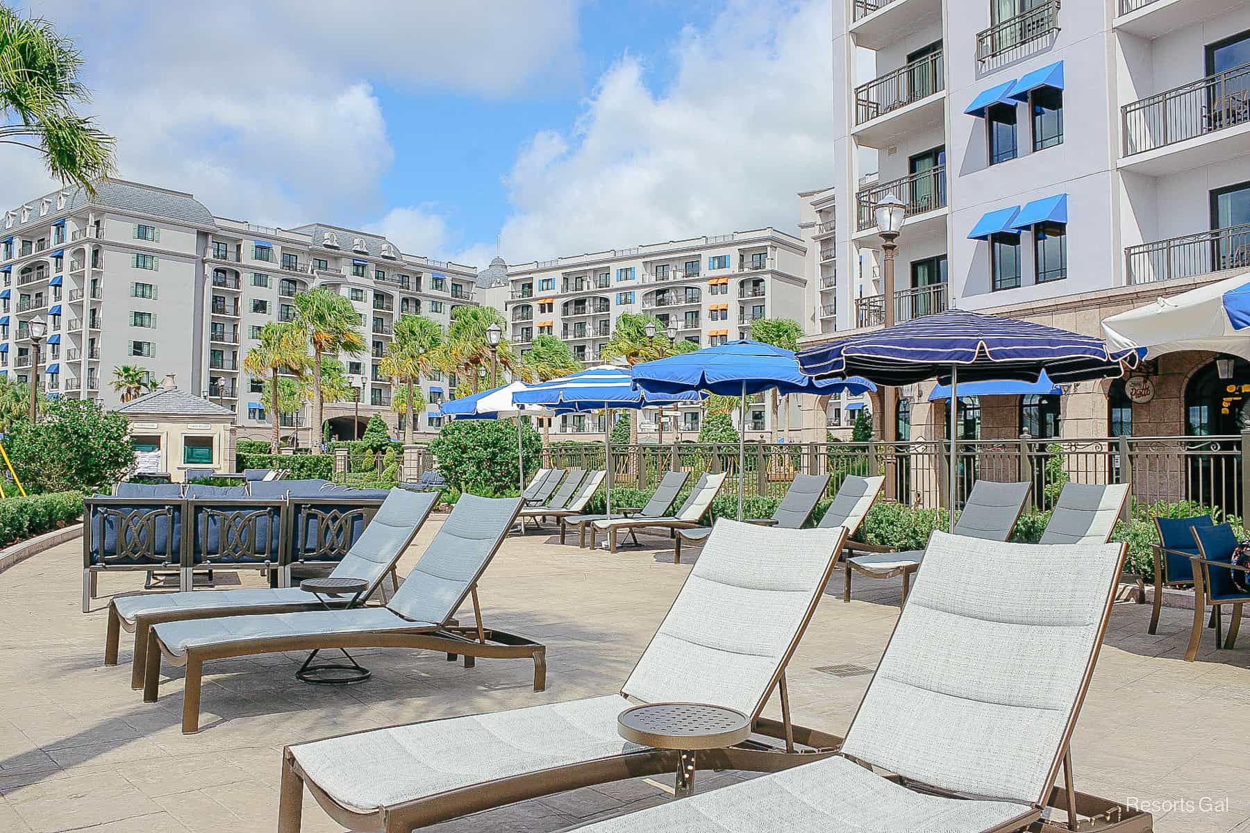 a row of lounge chairs and table and chairs with umbrellas behind it 