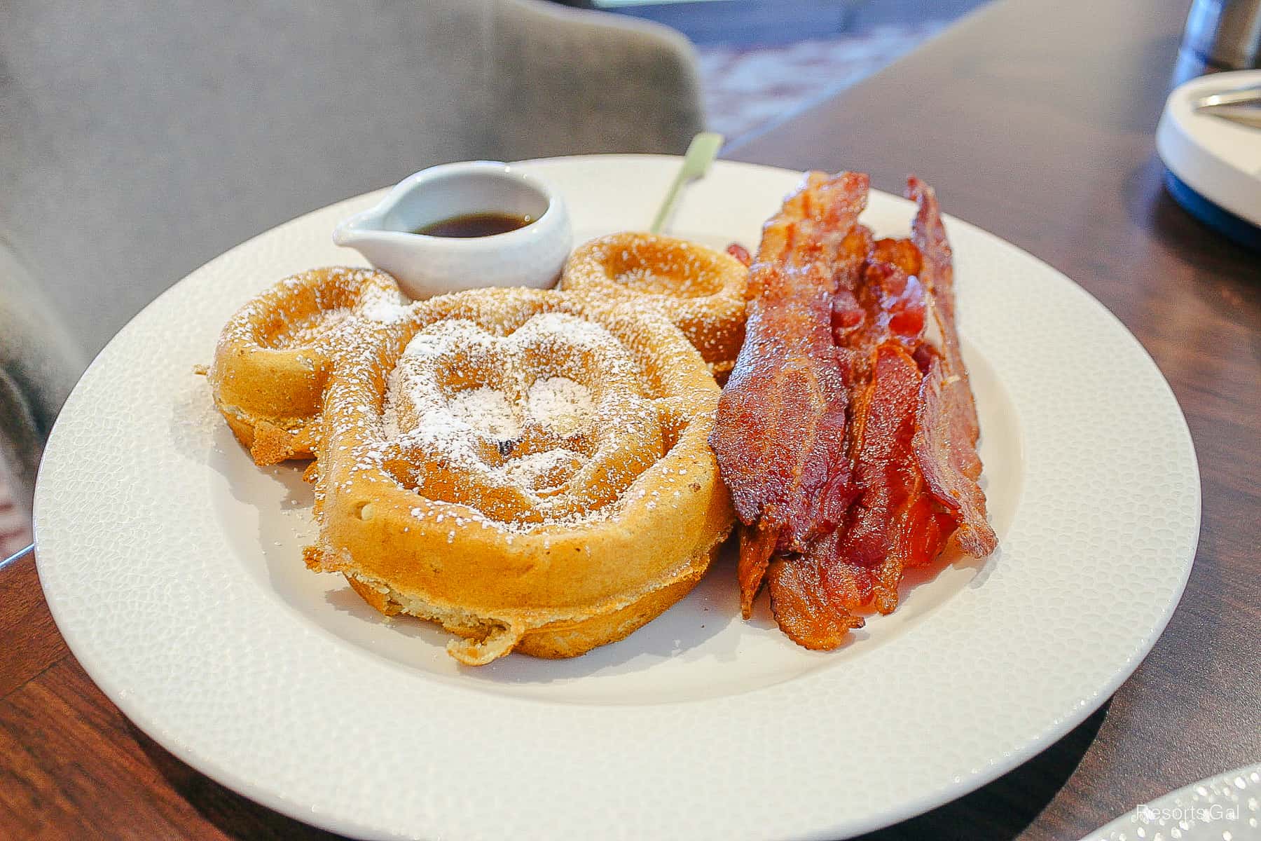 a white plate with a Mickey waffle and bacon 