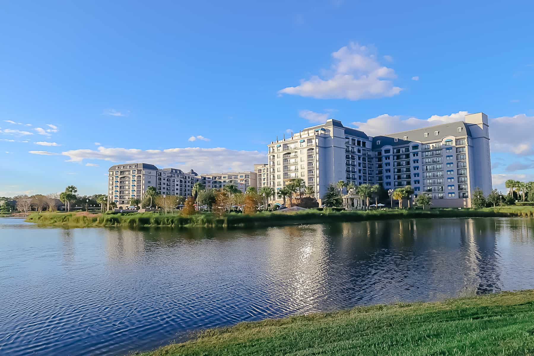 Disney's Riviera with the sun shining on sits in the background behind the lake. 