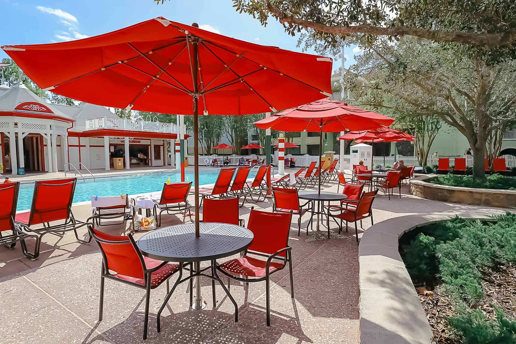 a table and chairs with red umbrella near the Grandstand Pool