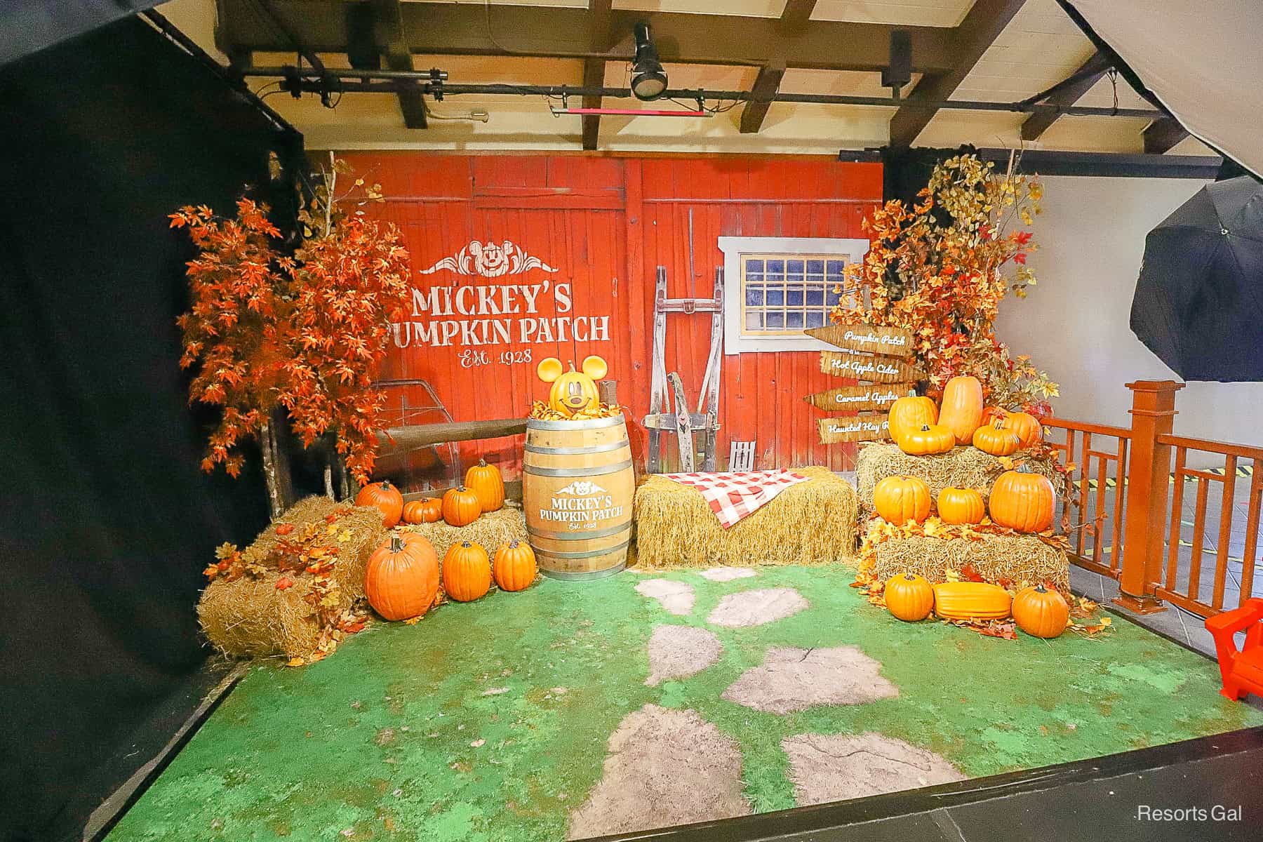 a staged backdrop with Mickey's Pumpkin Patch, bales of hay, and red barn look at Disney Springs PhotoPass Studio