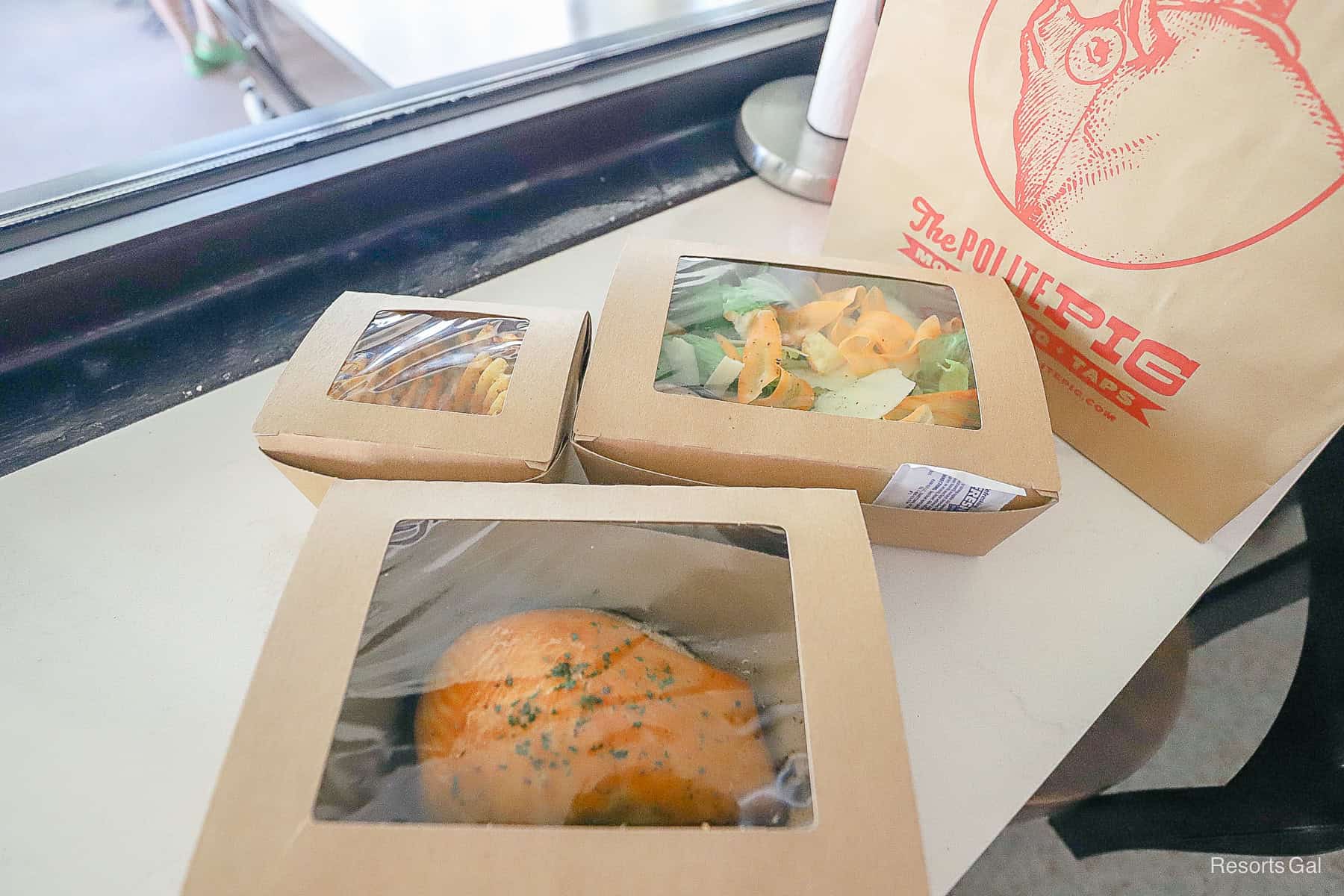 an order from Disney Springs packed to-go with a salmon filet, salad, and waffle fries